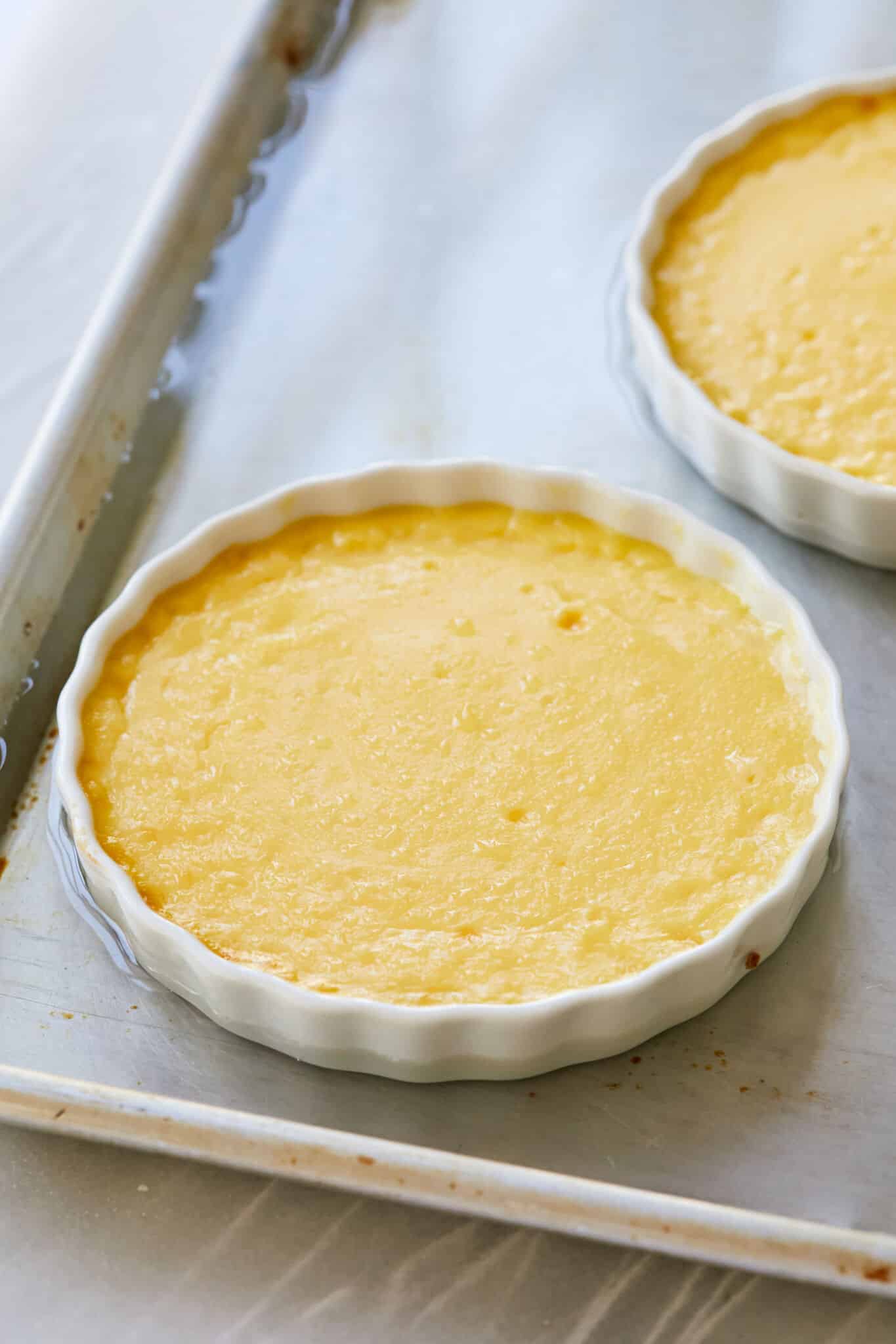 Two dishes of Passionfruit Crème Brûlée have been baked in a water bath and the edges are set but still slightly jiggly in the middle.