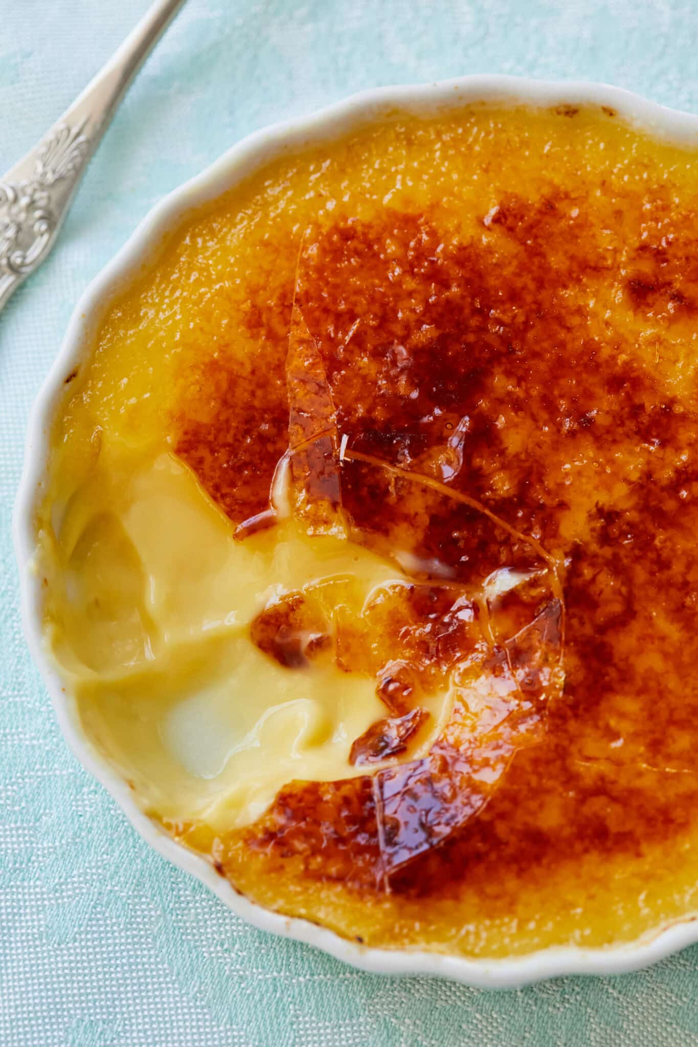 One bite has been taken from the Passionfruit Crème Brûlée. The close-up shot shows its silky smooth custard and crunchy caramelized top layer. 