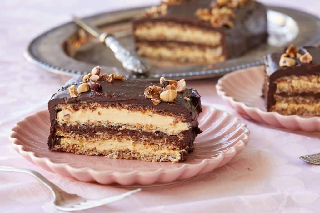 Side view of Marjolaine cakes with layers of almond meringue and buttercream frosting in between. Coated with with French chocolate buttercream.