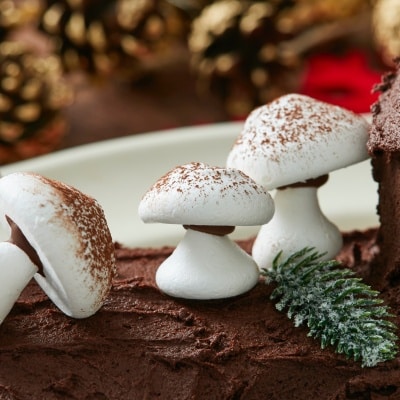 White Meringue Mushroom cookies dusted with cocoa powder are placed on Bûche de Noël as decoration.