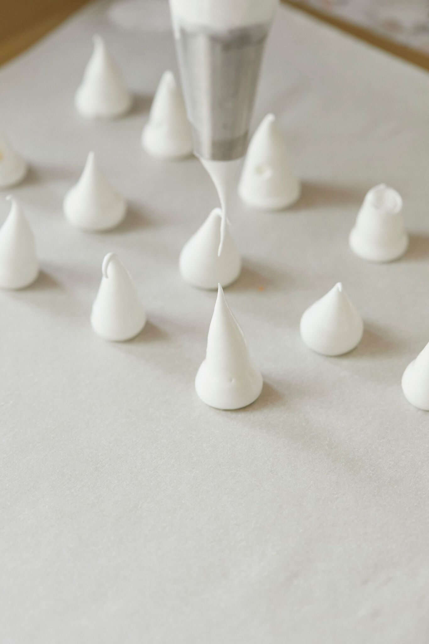 Step-by-step instruction on how to make Meringue Mushrooms : pipe whipped egg whites mixture onto parchment paper into mushroom stems.