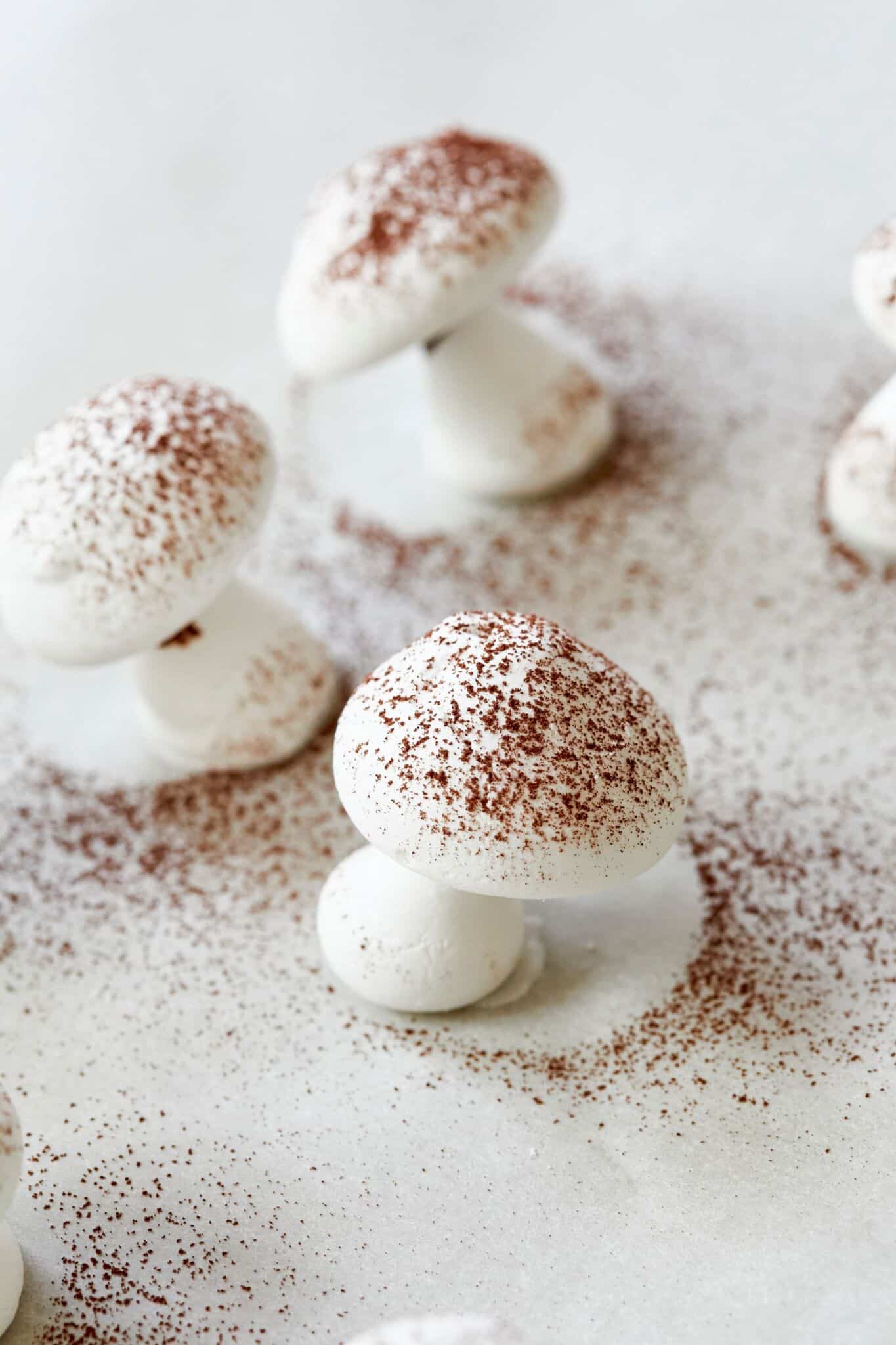 White Meringue Mushroom cookies are dusted with chocolate-color cocoa powder, ready for Bûche de Noël.