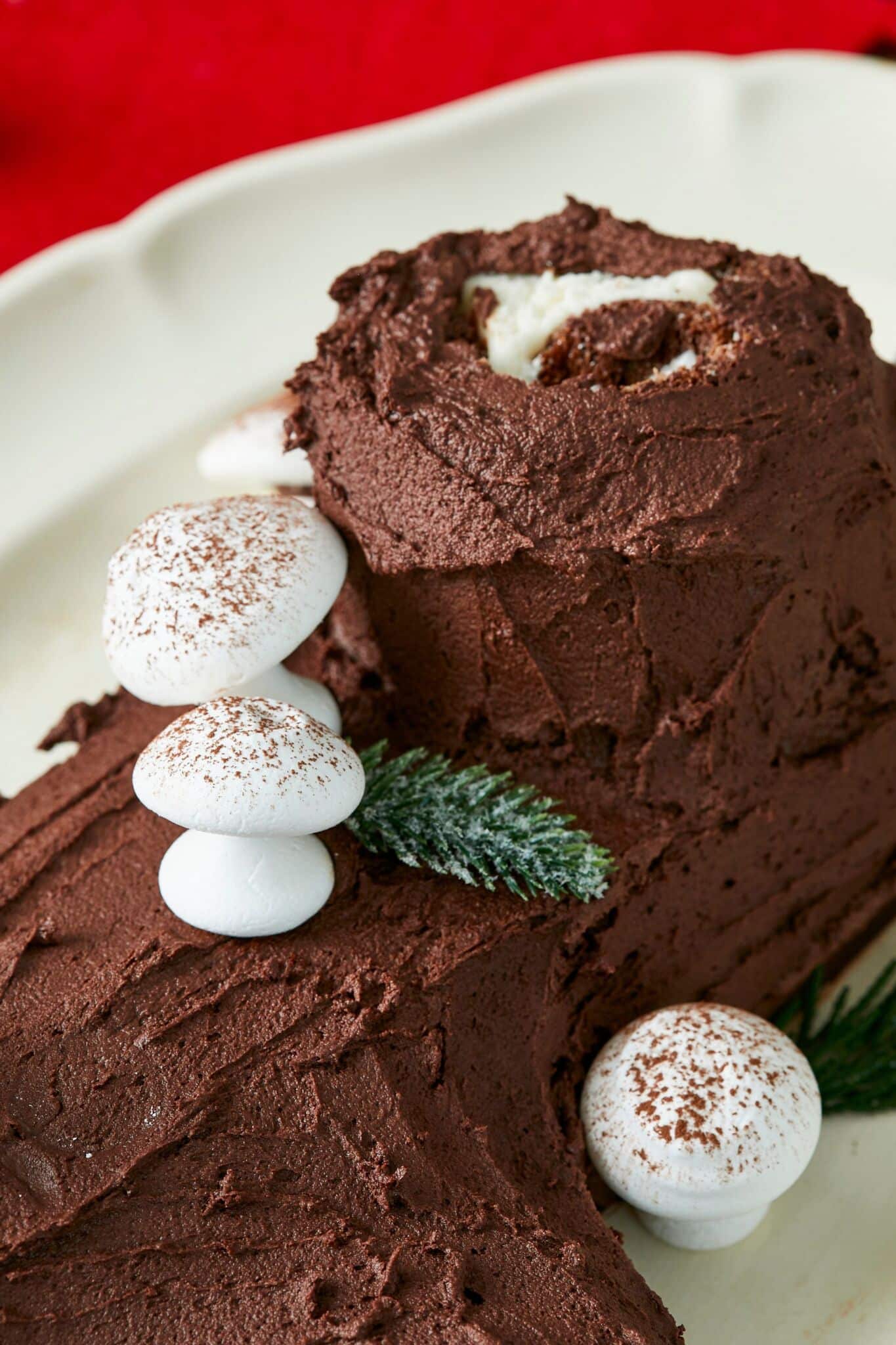 White Meringue Mushroom cookies are placed on the frosted chocolate-color Bûche de Noël.