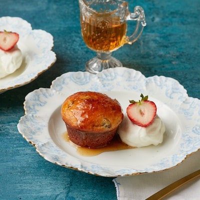 Two soft, delicate Baba au Rhum (Classic Rum Baba) cakes are served with fresh strawberry and whipped cream. Syrup has been drizzled from top to bottom.