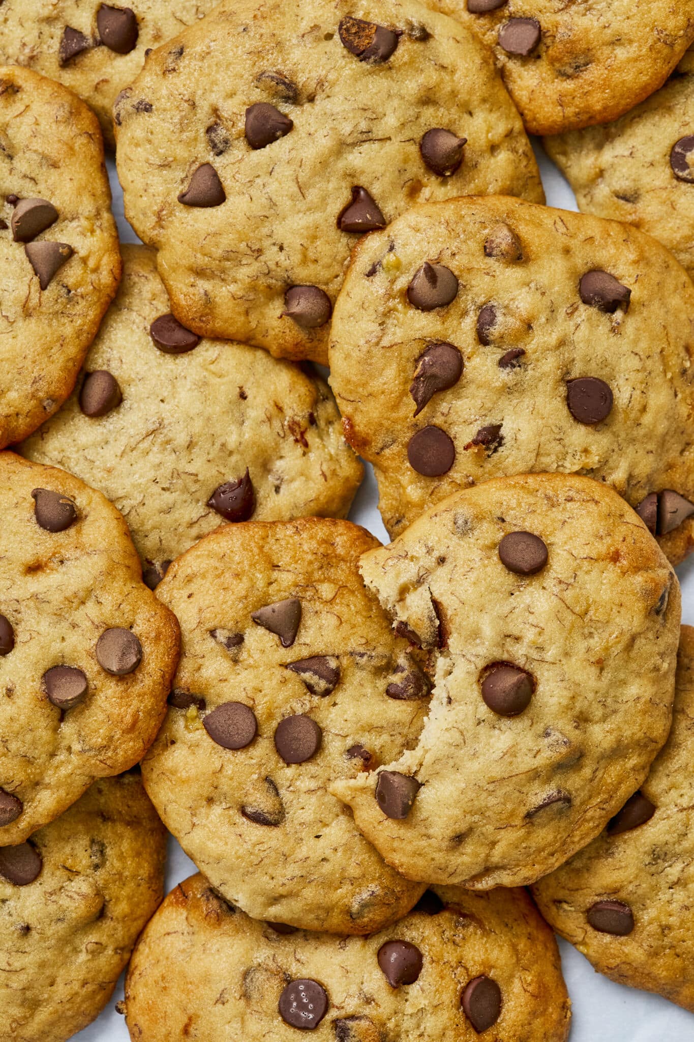 A close-up shot at Banana Bread Chocolate Chip Cookies shows the golden brown edges and golden center with banana fibers.