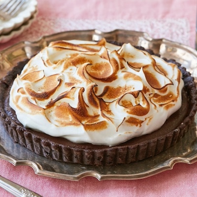 Irresistible Whiskey Chocolate Meringue Tart is served on a silver platter. It has decadent chocolate crust, rich and smooth chocolate filling, topped with velvety toasted meringue.