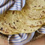 A stack of Homemade Corn Tortillas are golden and bubbly on top.