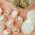 Thin, delicate Homemade Dumpling Wrappers with some dumplings. A bowl of filling is on the side.