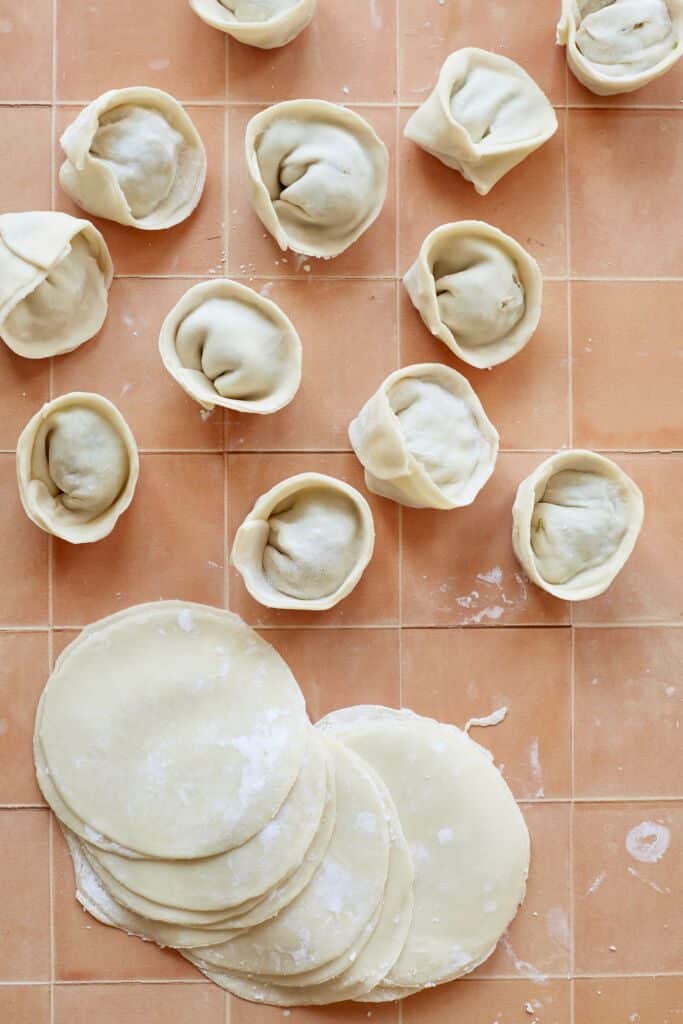 Thin pliable Homemade Dumpling Wrappers with some dumplings.