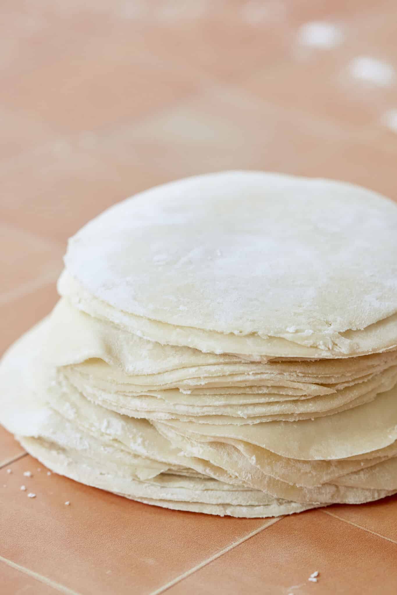 A stack of Homemade Dumpling Wrappers with flour in between to prevent from sticking to each other. 