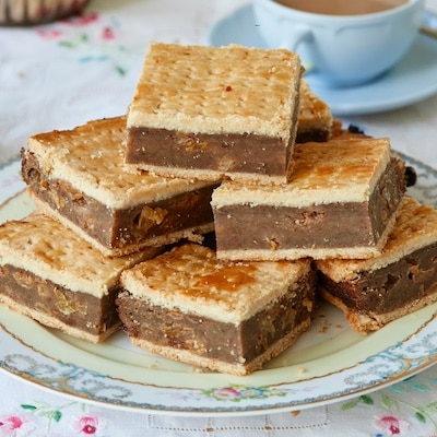 A plate of Irish Gum Cakes are served with tea. The Fur Cakes have golden flaky top and bottom crust, filled with moist breadcrumbs, spices, and sweet raisins.