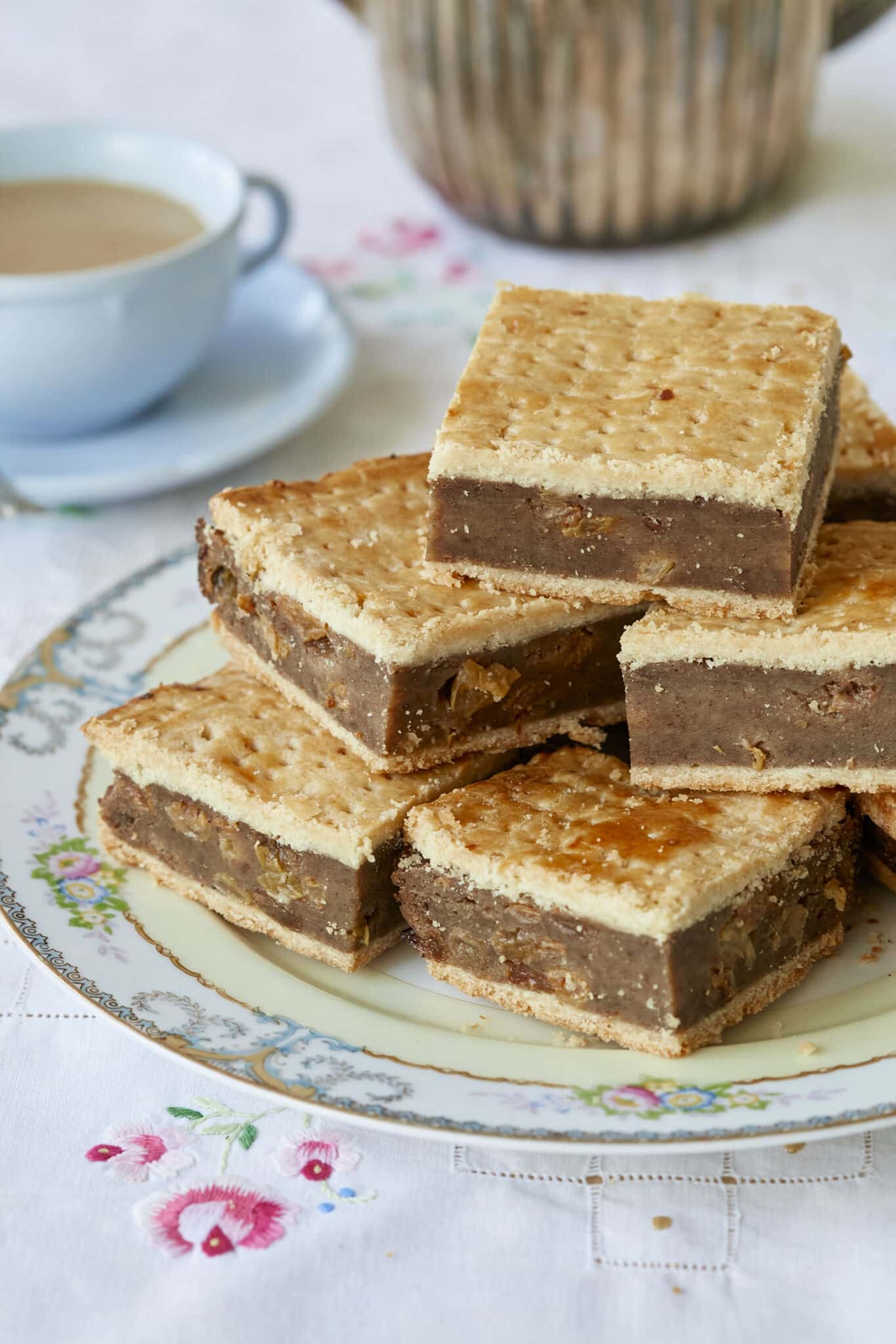 A plate of Irish Gum Cakes are served with tea. The Fur Cakes have flaky top and bottom crust, filled with moist breadcrumbs, spices, and sweet raisins. 