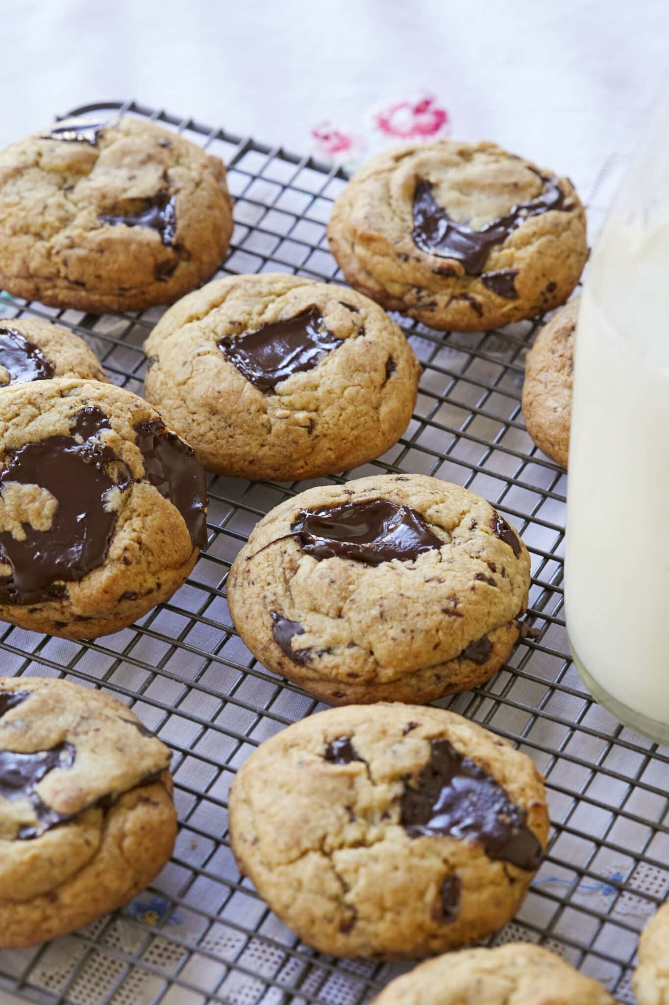 Sourdough Chocolate Chip cookies are baked golden brown with pools of chocolate throughout are cooling on a wire rack. They're paired with milk.