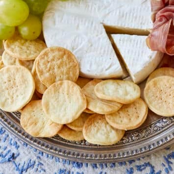 Water Crackers are paired with grapes, cheese, and salami on a charcuterie board.