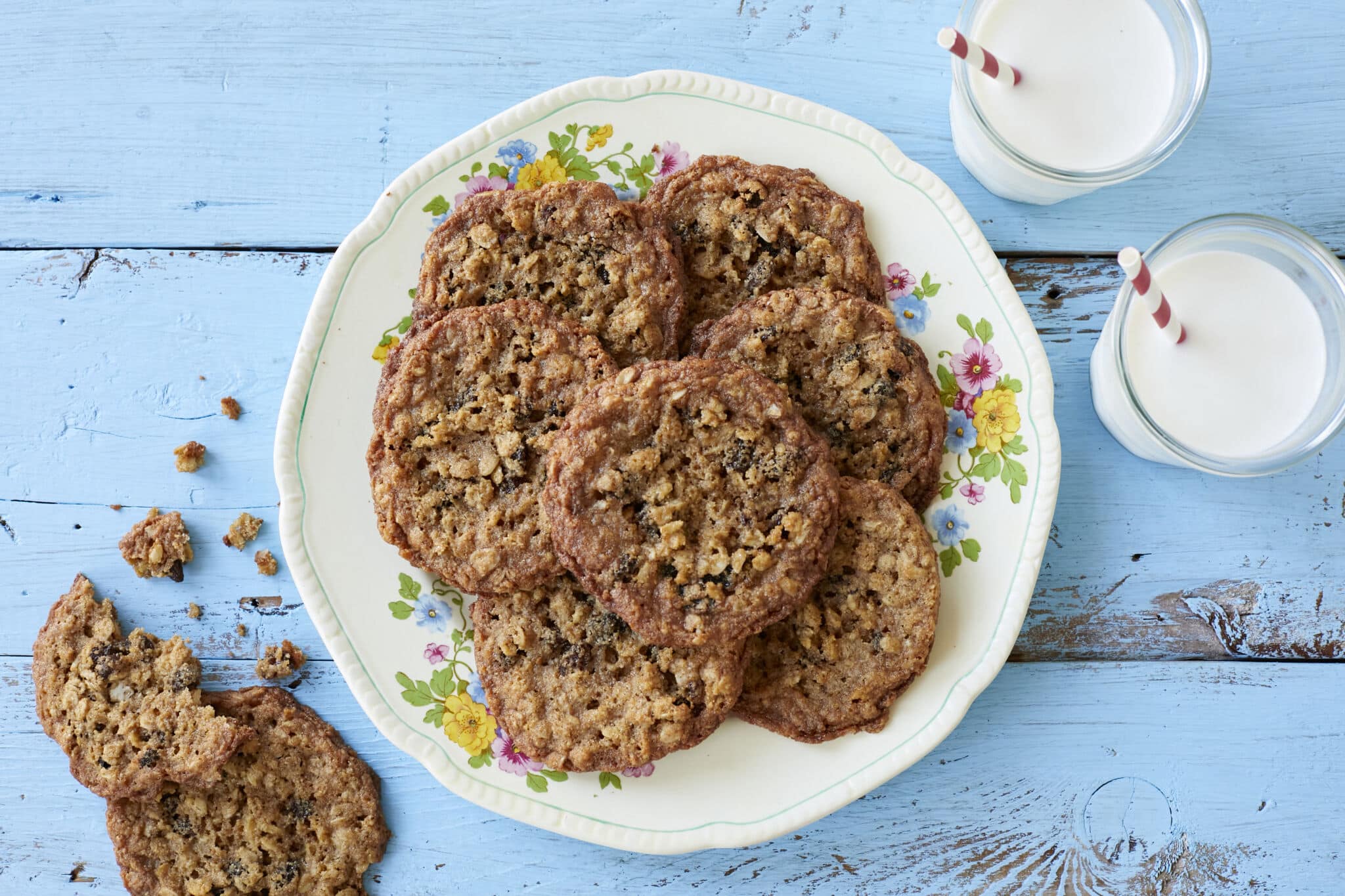 Crispy, chewy Almond Flour Cinnamon Raisin Cookies are served on a big platter with two glasses of milk.