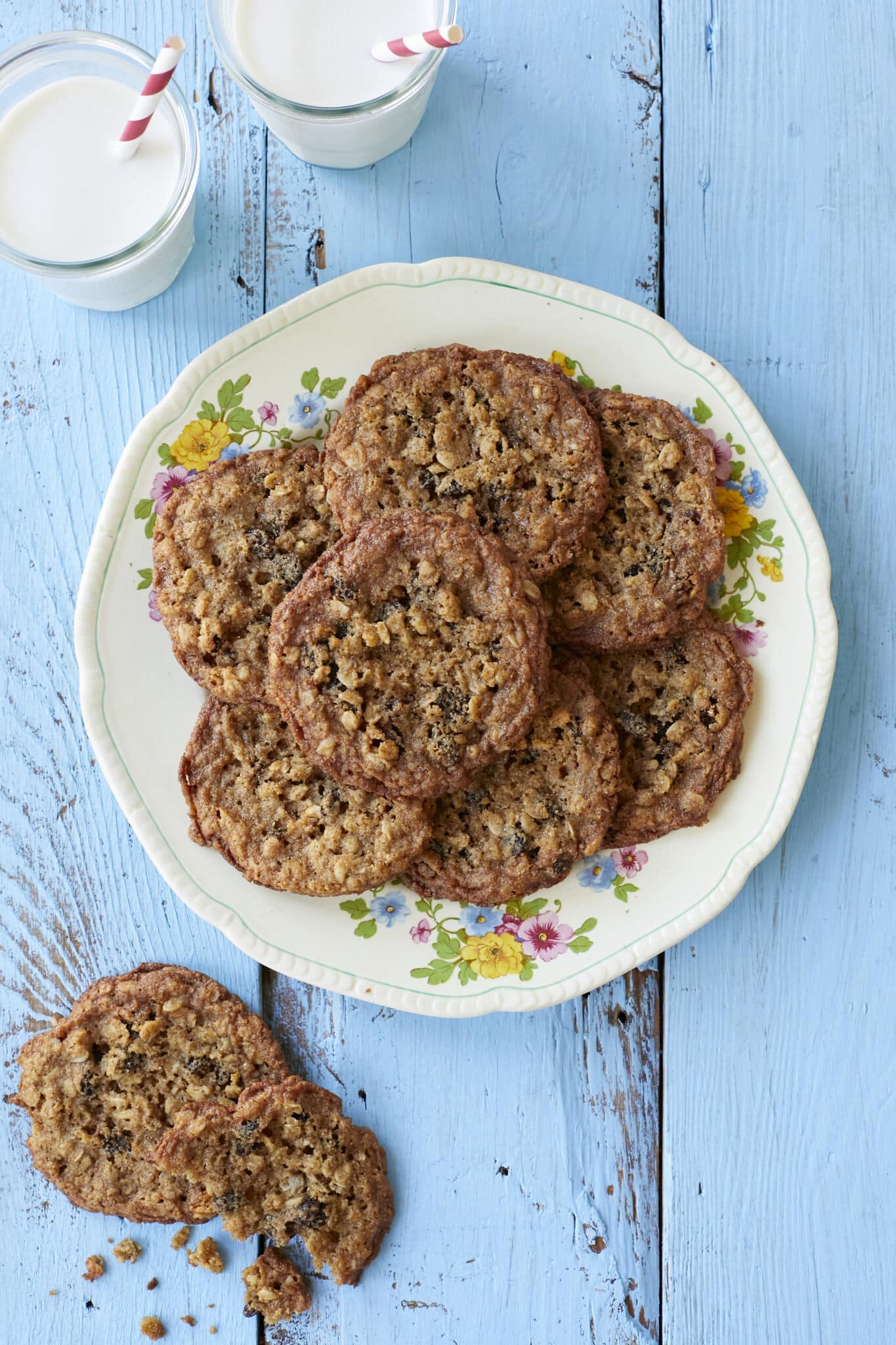 Crispy, chewy Almond Flour Cinnamon Raisin Cookies are served on a big platter with two glasses of milk. 