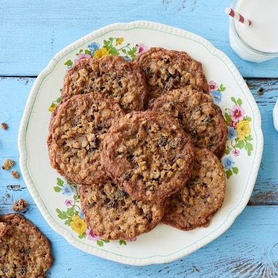 Crispy, chewy Almond Flour Cinnamon Raisin Cookies are served on a big platter with two glasses of milk.