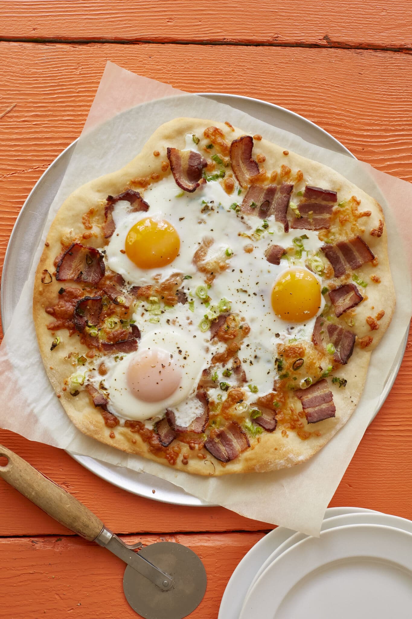 Wholesome breakfast pizza has golden and crispy crust, with smoky bacon, green onions, and sunny-side-up eggs bringing layers of savory flavor.