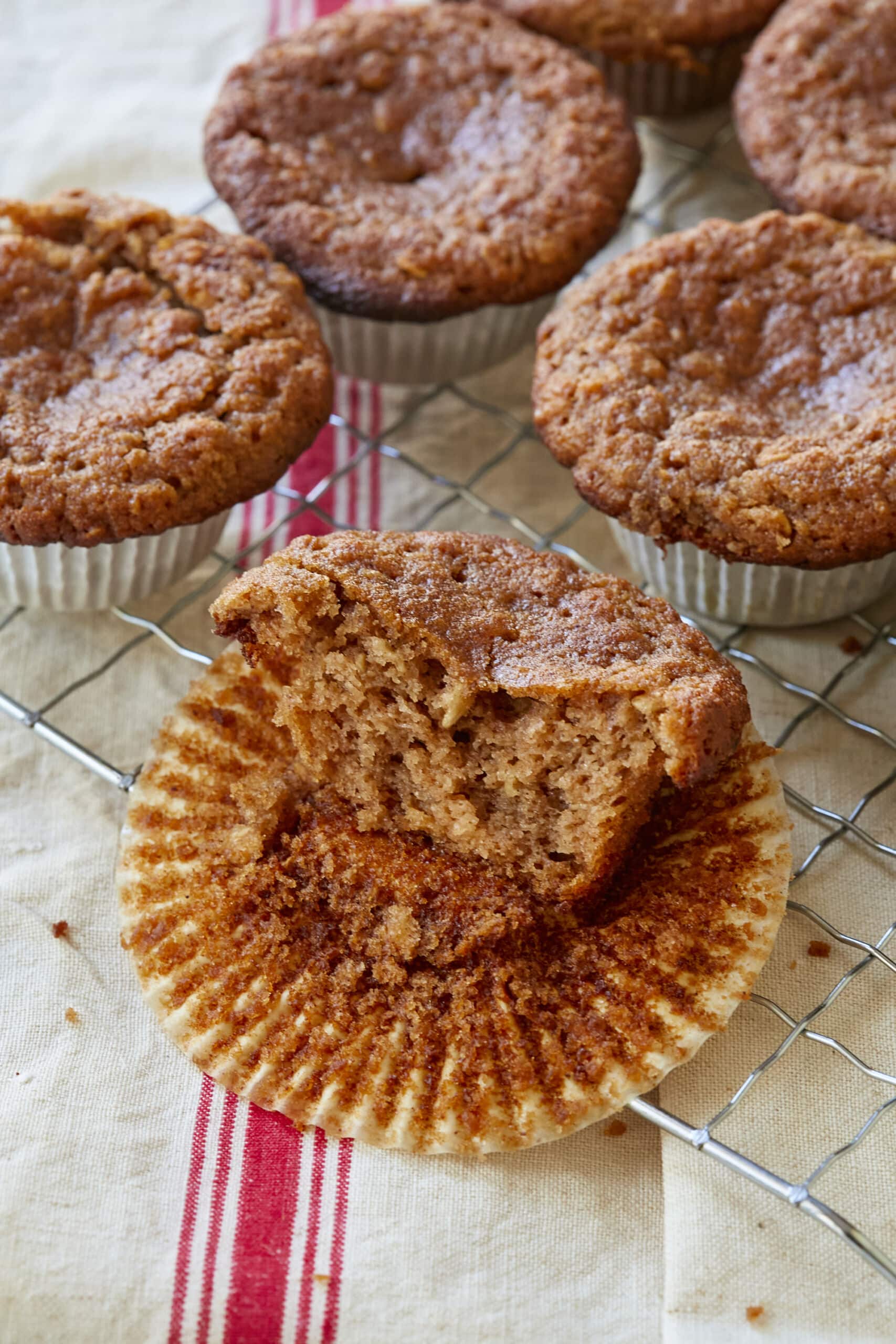 Golden brown Healthy Almond Flour Muffins are cooling on a wire rack. One muffin has been eaten by half. 