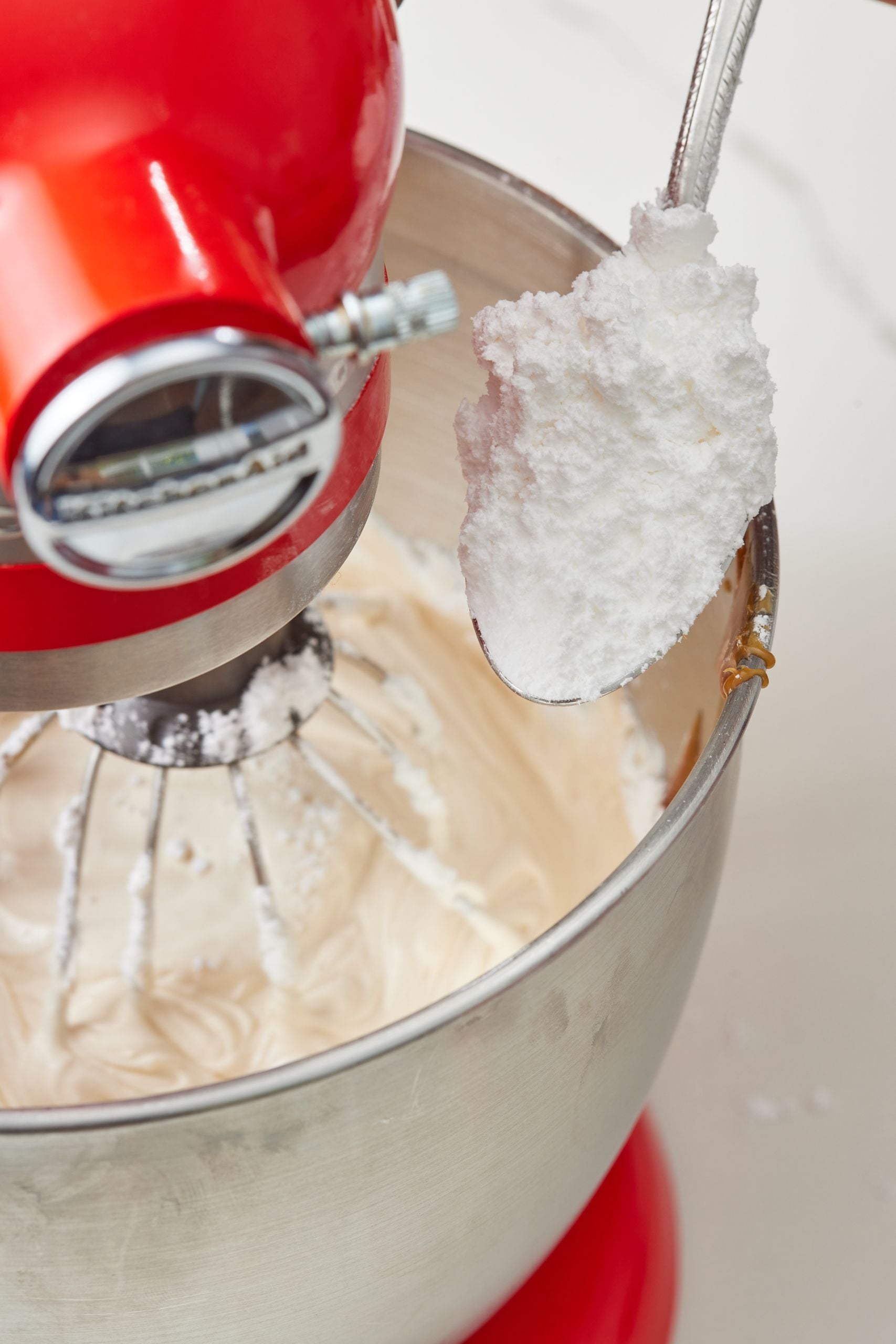 Gradually add the sifted powdered sugar, one spoonful at a time.