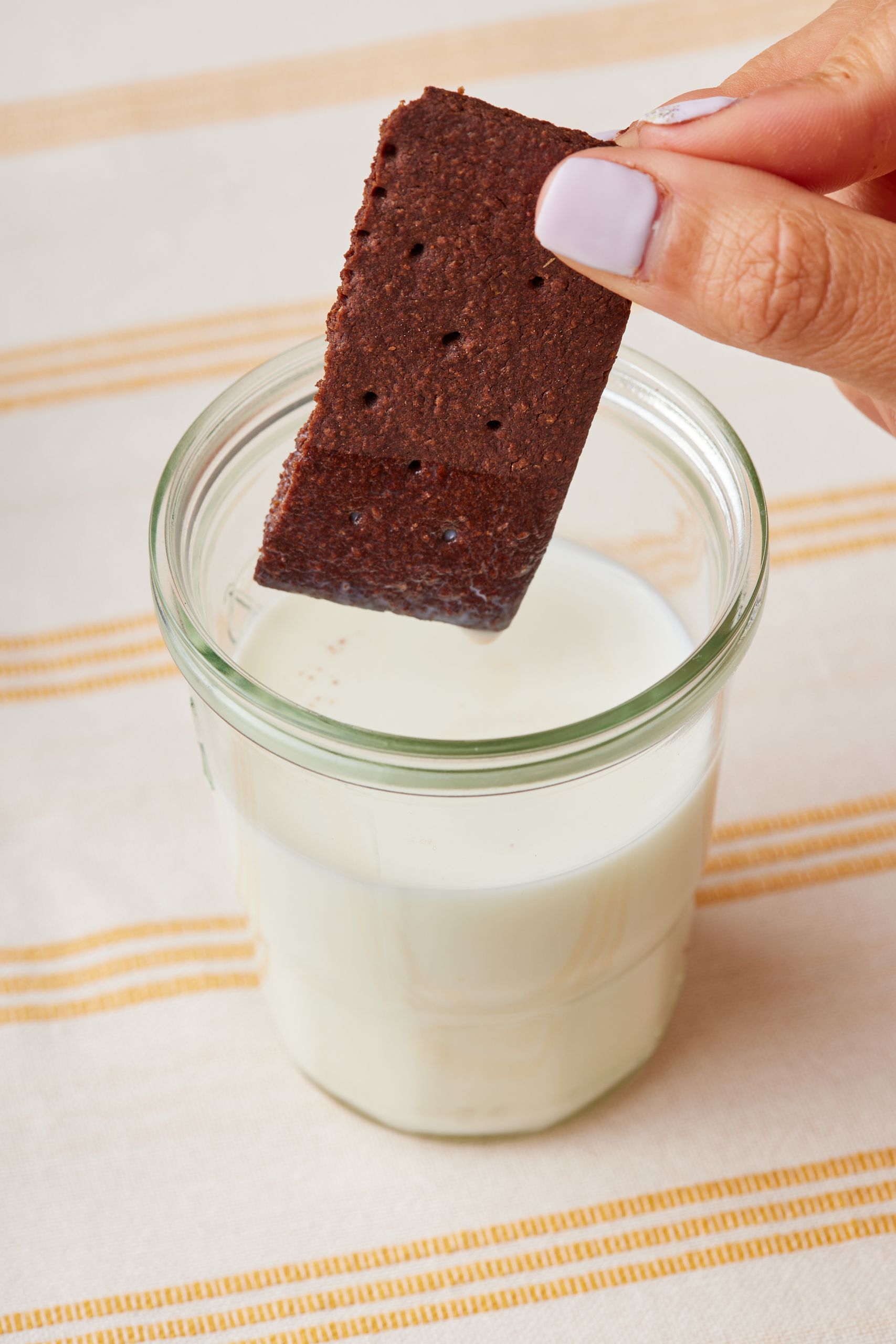 One chocolate graham dipping into milk .