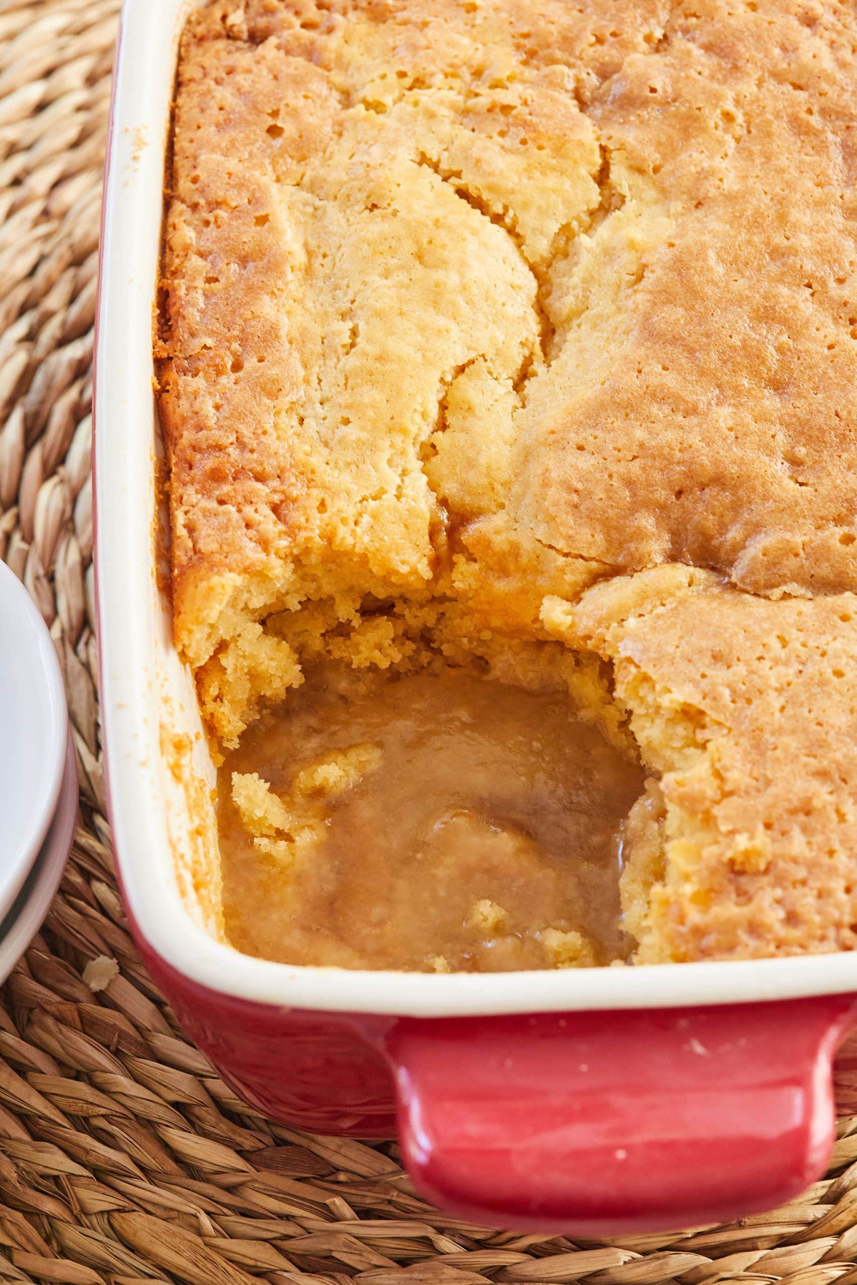 Golden Self Saucing Butterscotch pudding in a baking dish with one scoop taken, showing the sauce underneath. 