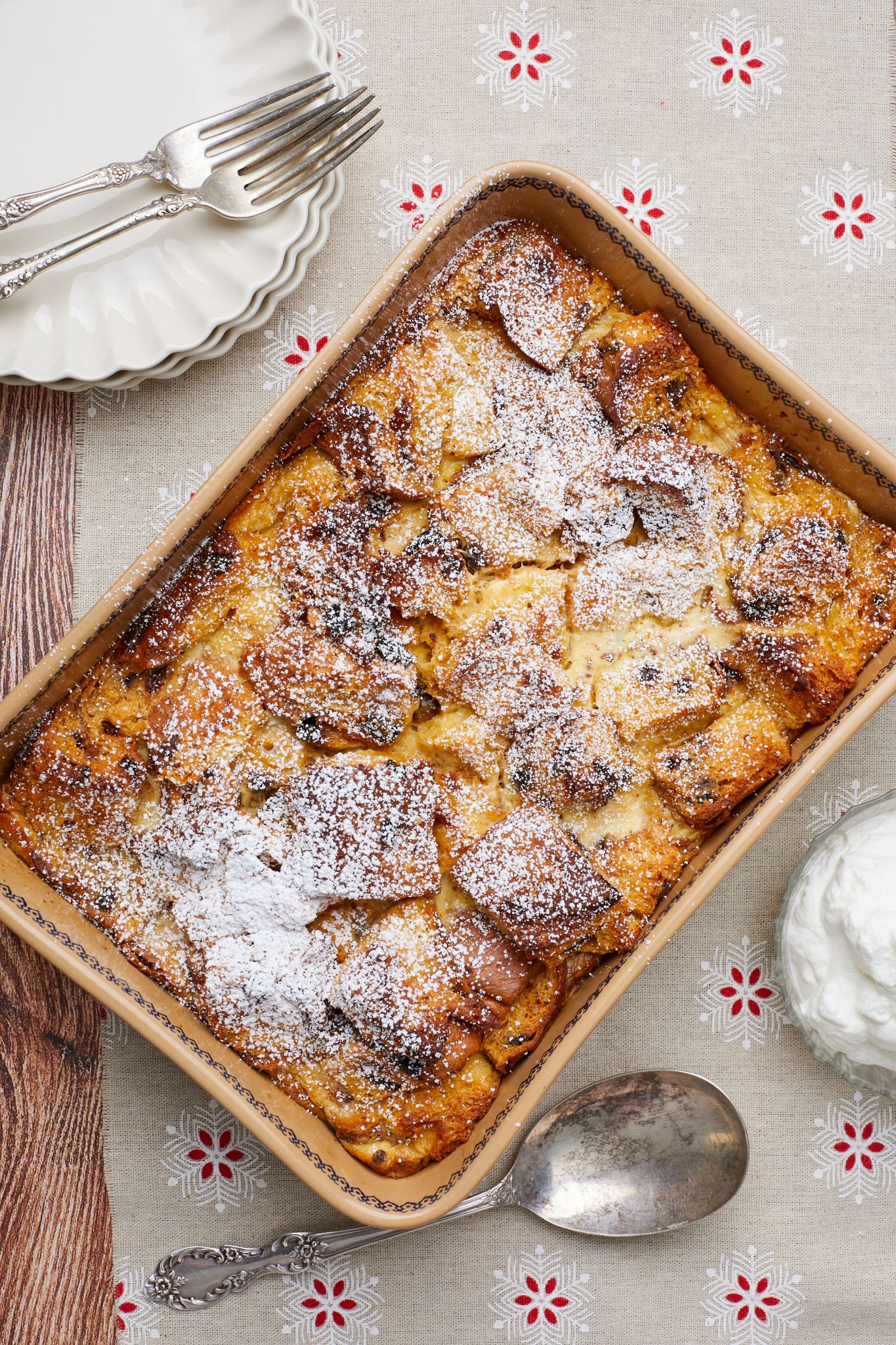 The bread pudding with Panettone is baked until golden brown on top and dusted with powdered sugar, ready to be served with whipped cream on the side.