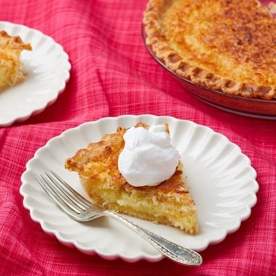 Coconut Custard Pied is served on dessert plates with whipped cream.