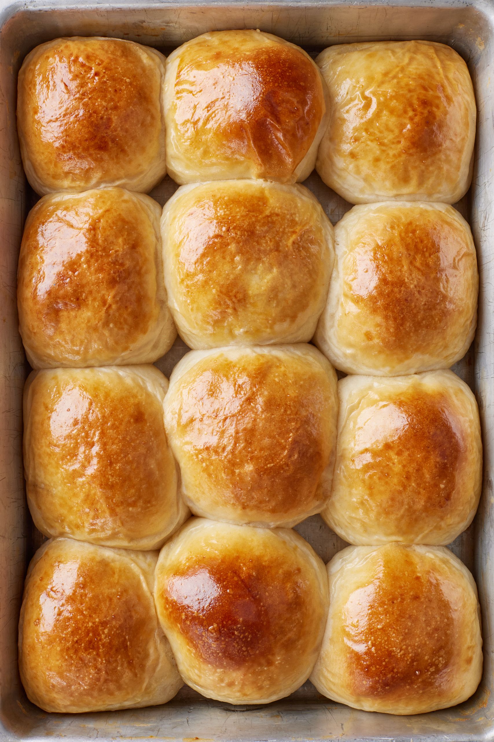 A tray of golden brown Sourdough Dinner Rolls.