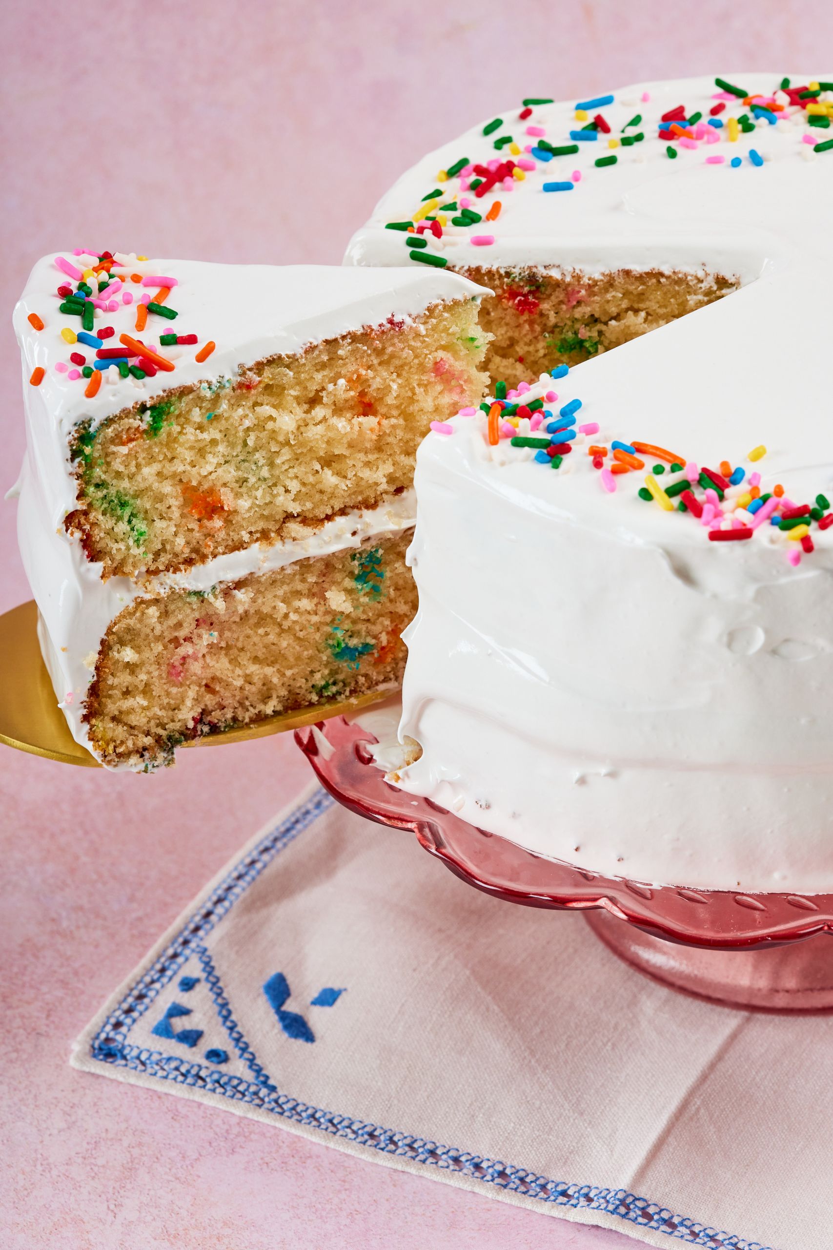 A close-up shot at the slice that has been cut off the whole cake, shows the most crumb, smooth frosting between two layers of cake and around the cake. 
