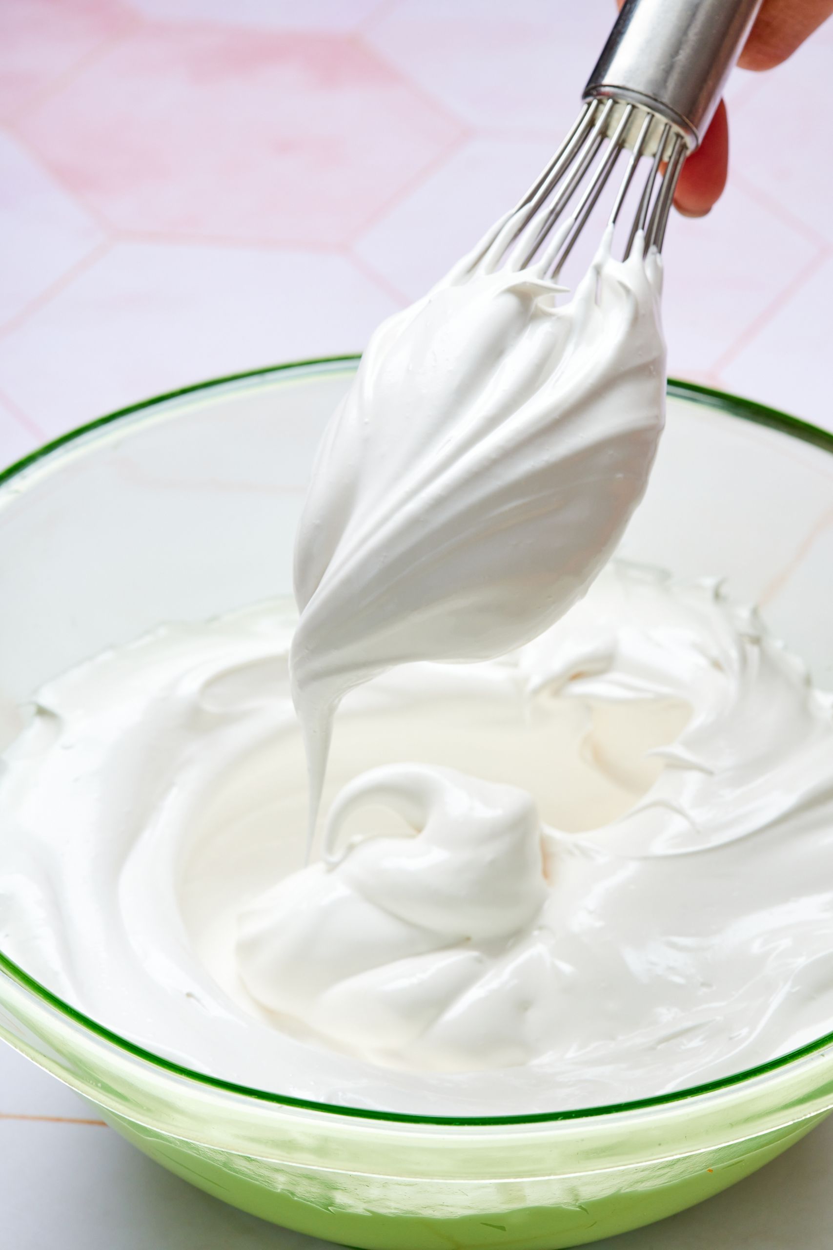 7 Minute frosting in a glass mixing bowl. The whisk is lift up some smooth frosting. 