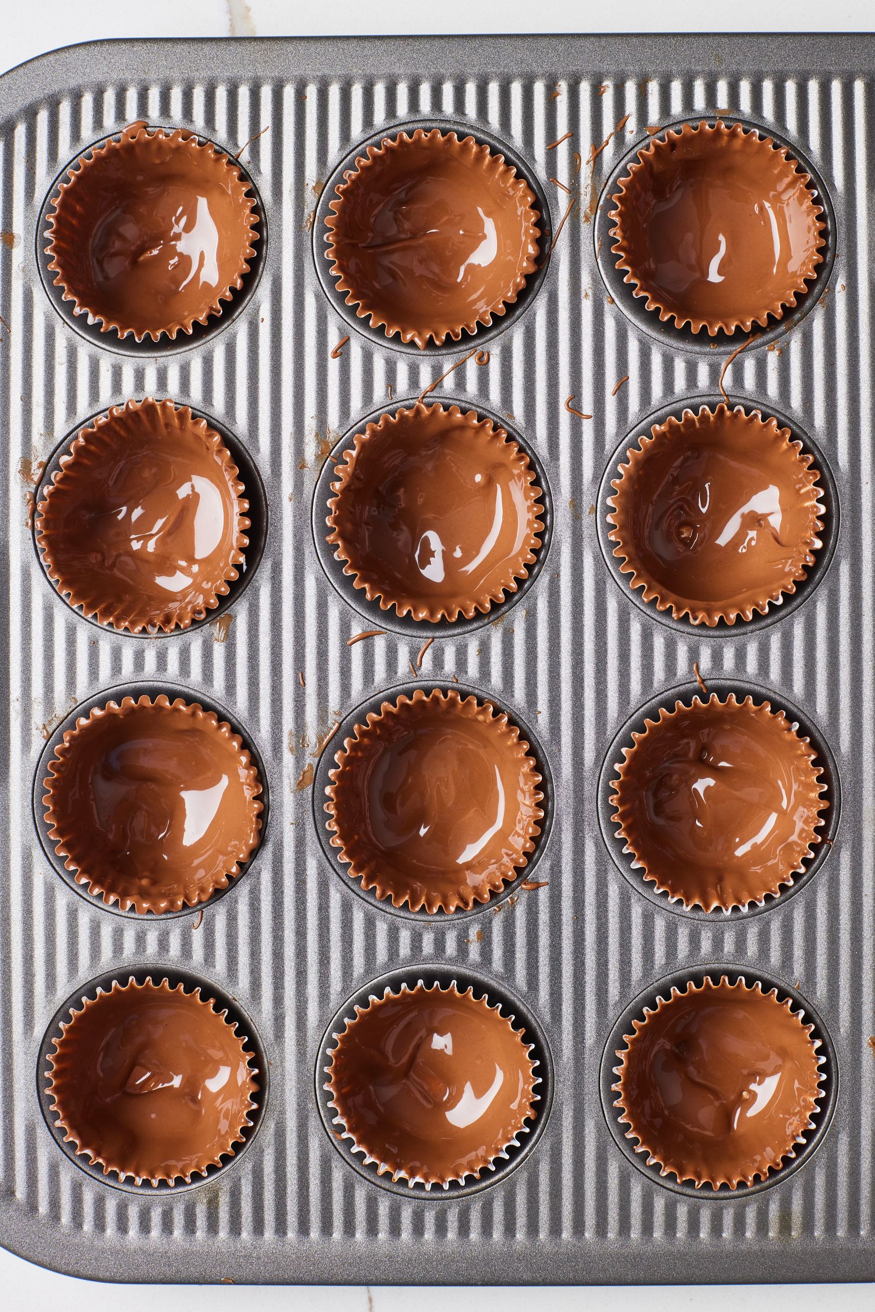 Step-by-step instructions on how to make Reese's Peanut Butter Cups: coat each liner with melted chocolate and chill to set. 