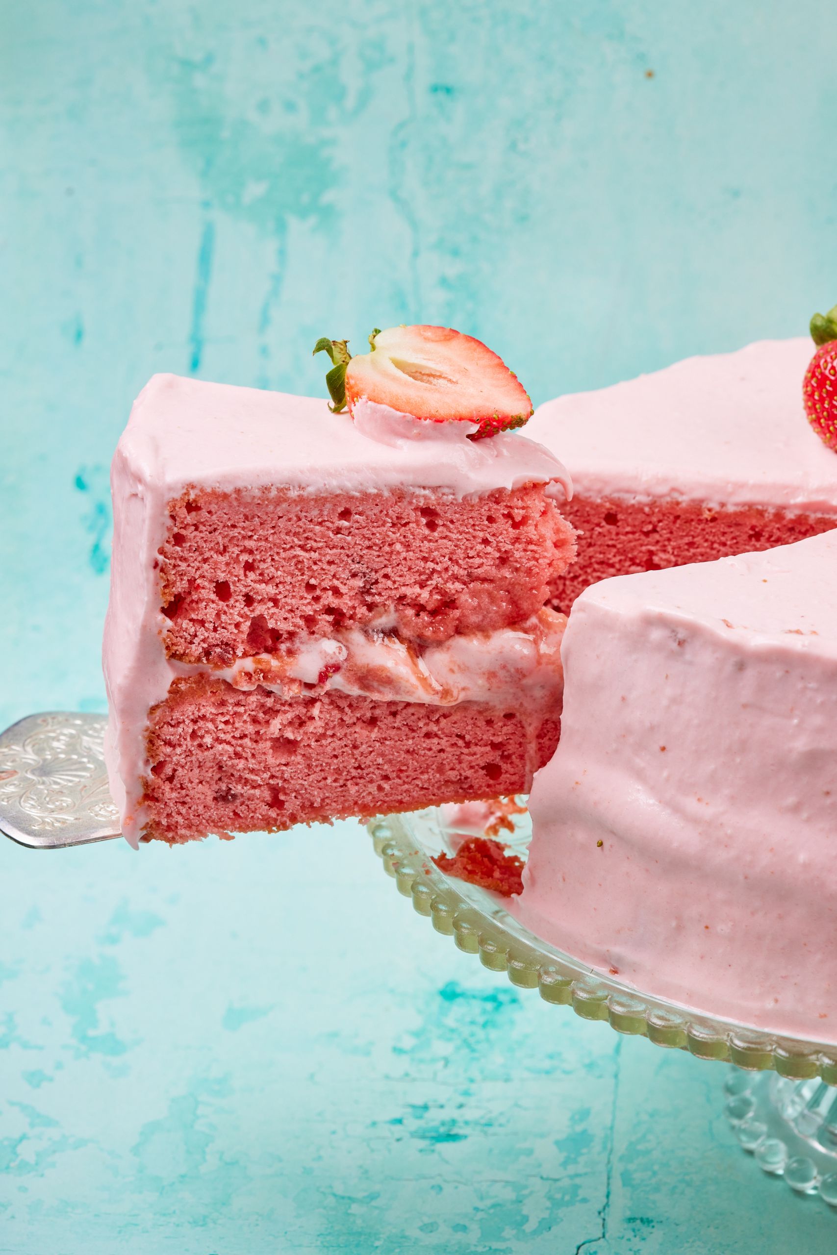 A close-up shot at a slice that's being cut and lifted away from the cake, showing the moist crumb and smooth frosting. 