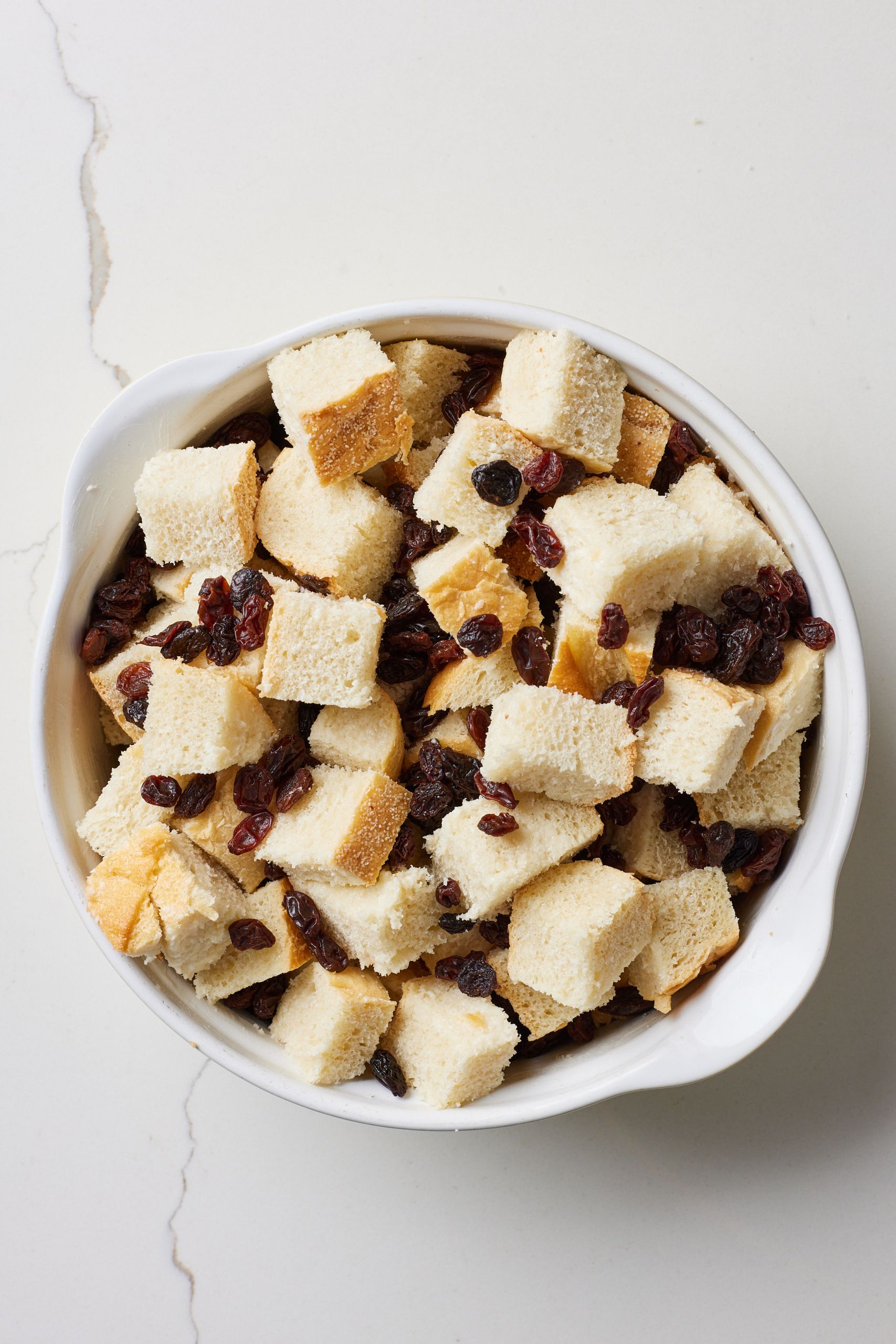 Step-by-step instructions on how to make Bread Butter Pudding with Whiskey sauce: cut bread into small cubes and scatter over raisins and add into a buttered 2-quart (2 liter) baking dish. 