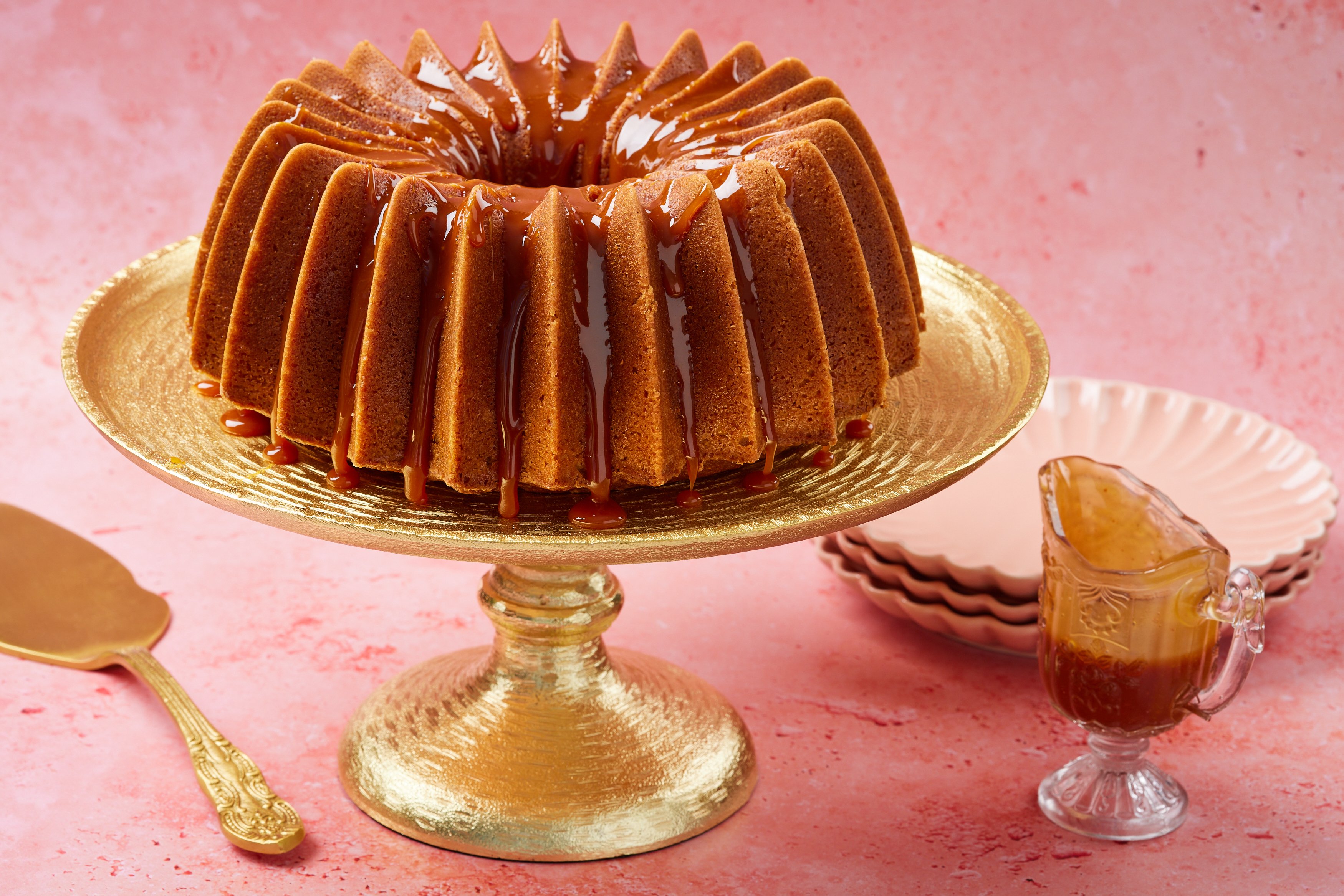 A whole Whiskey Cake on a cake stand shows its golden brown color, moist fine crumb and glossy glaze.