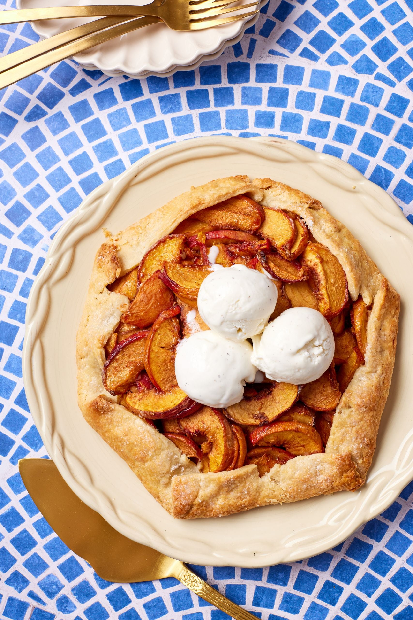 A top-down view of an Easy Peach Tart/ galette, with golden crust, juicy peaches, and ice cream on top. 