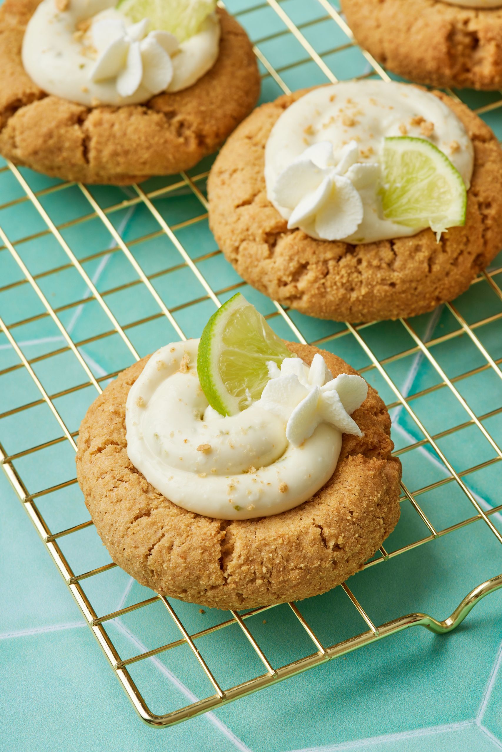 A close-up shot at 3 big Key Lime Pie cookies on the cooling rack, topped with filling, lime slices and zest