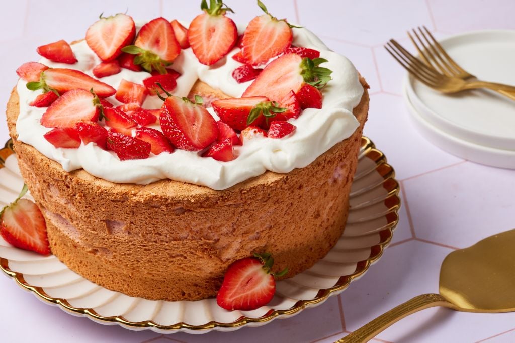Strawberry Angel Food Cake has golden crust and topped with softly whipped cream with fresh strawberry slices