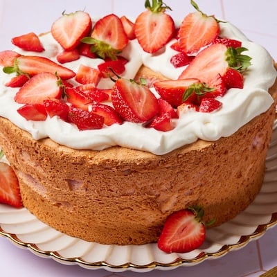 Strawberry Angel Food Cake has golden crust and topped with softly whipped cream with fresh strawberry slices
