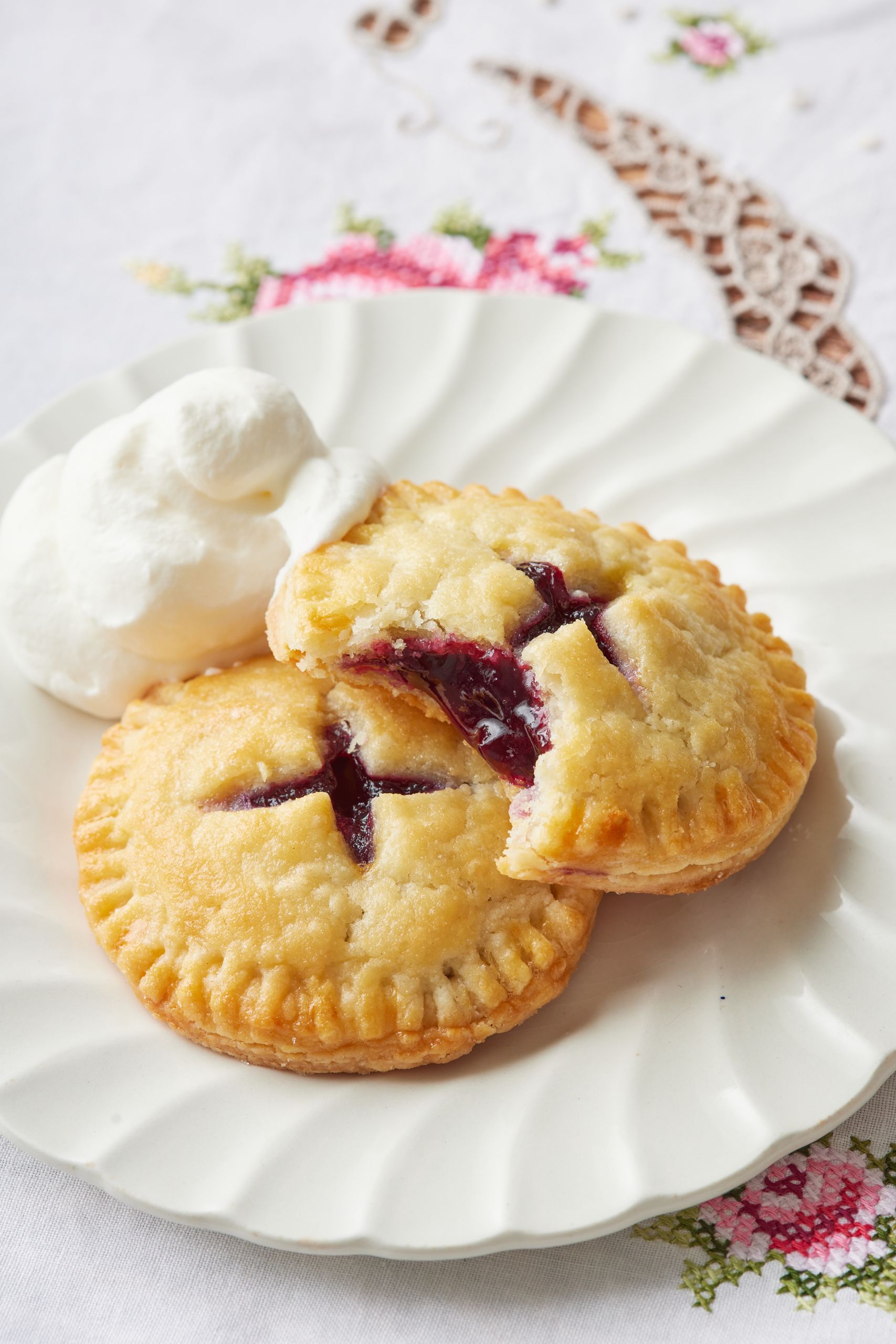 Two cookies served on a plate with whipped cream, with one of them with one bite taken. 