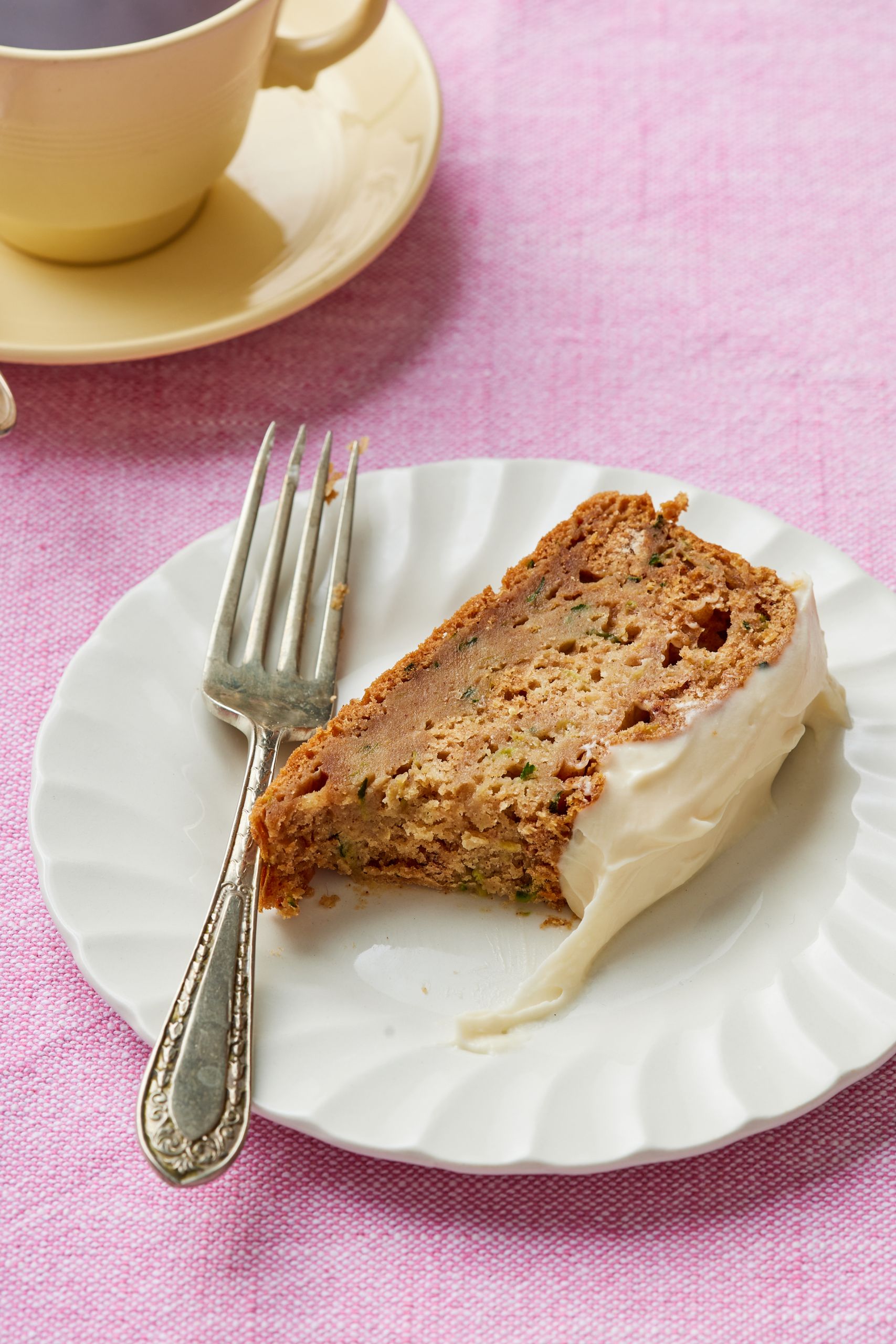 A slice of zucchini bread is served on a dessert plate with one bite taken. 