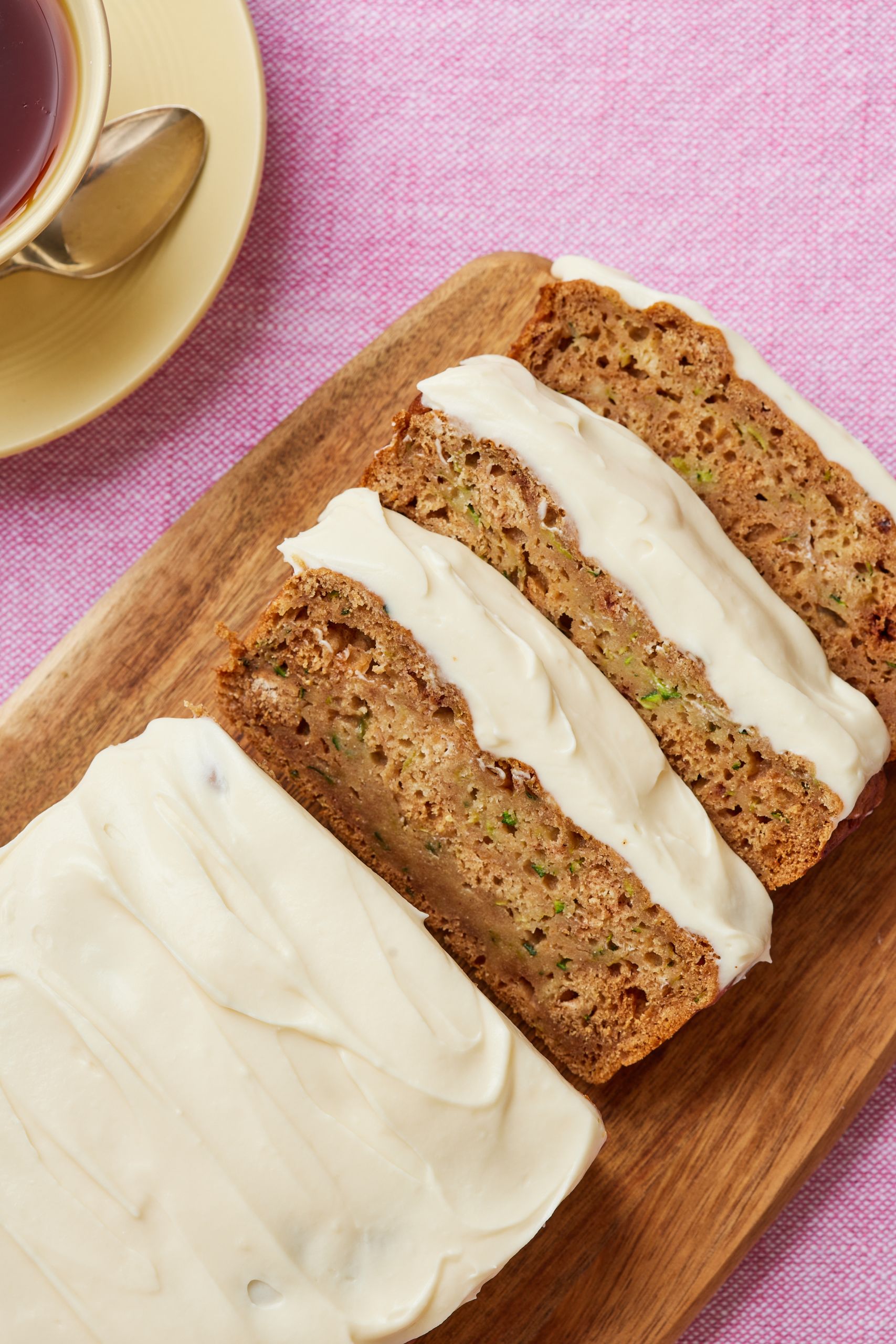 Apple Zucchini Bread served with tea. It's frosted and half loaf is sliced.