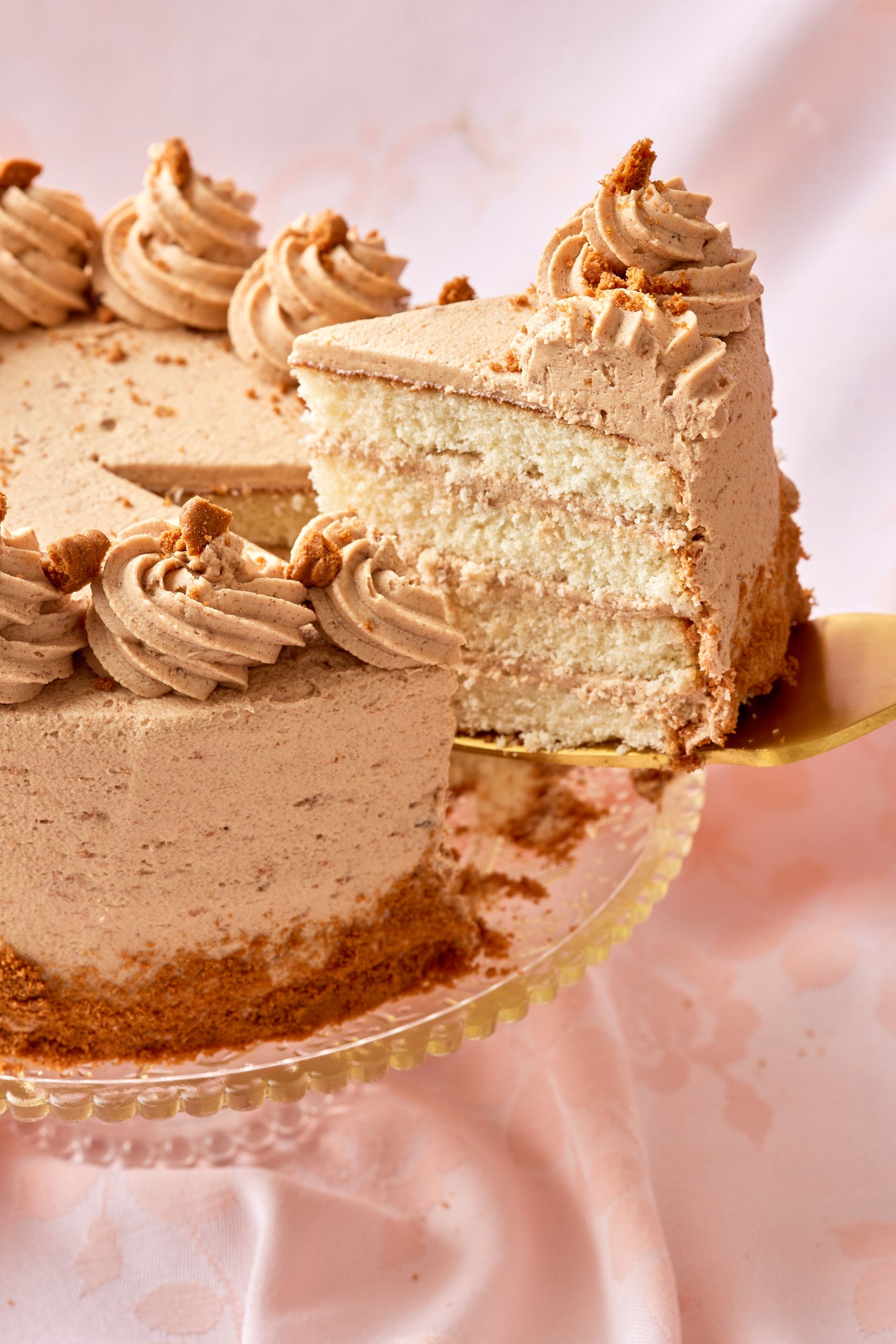One slice is being cut from the whole cake, which shows the layers of moist cake and smooth frosting. 