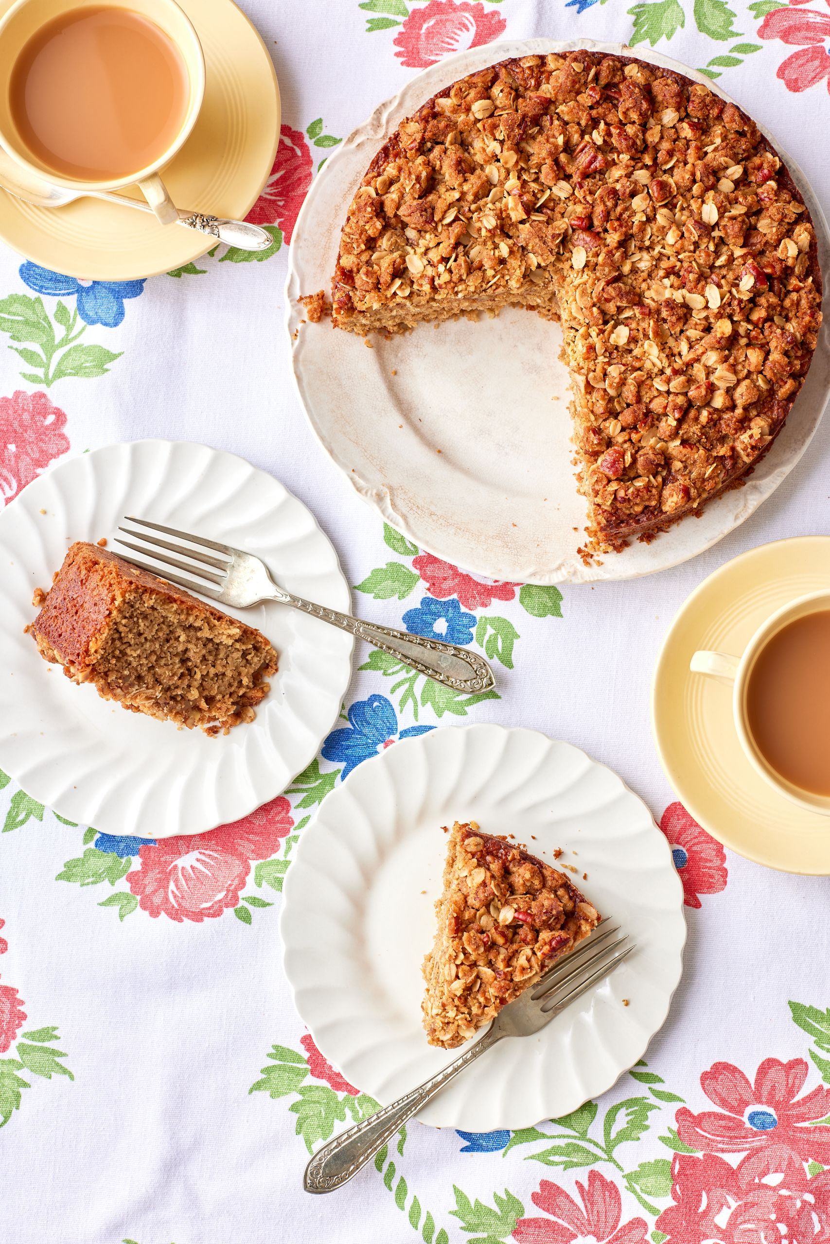Top down view of two slices of apple oatmeal cake served with tea, with the remaining cake on the side. 