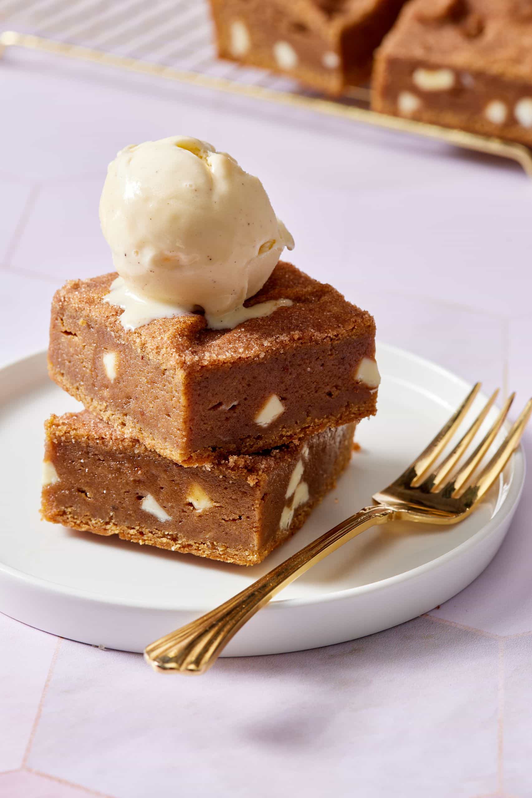 Two squares of pumpkin blondies stacked together and served with ice cream on top. 