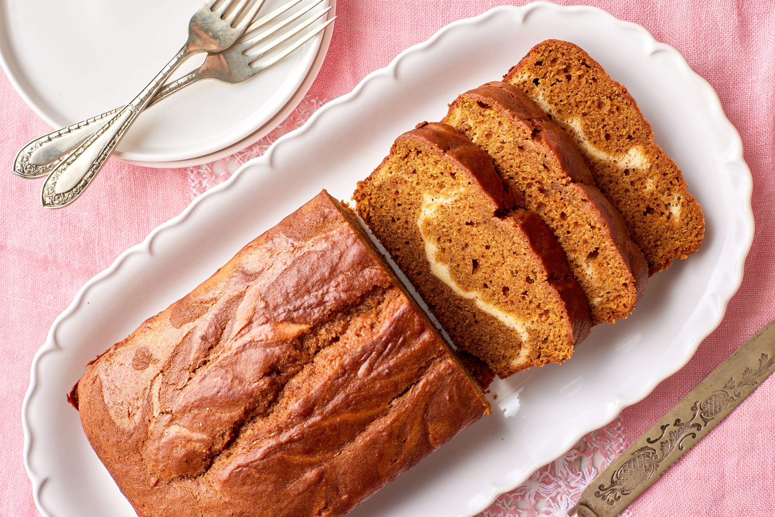 Top down view of Pumpkin Cream Cheese bread on a platter, with half loaf sliced.