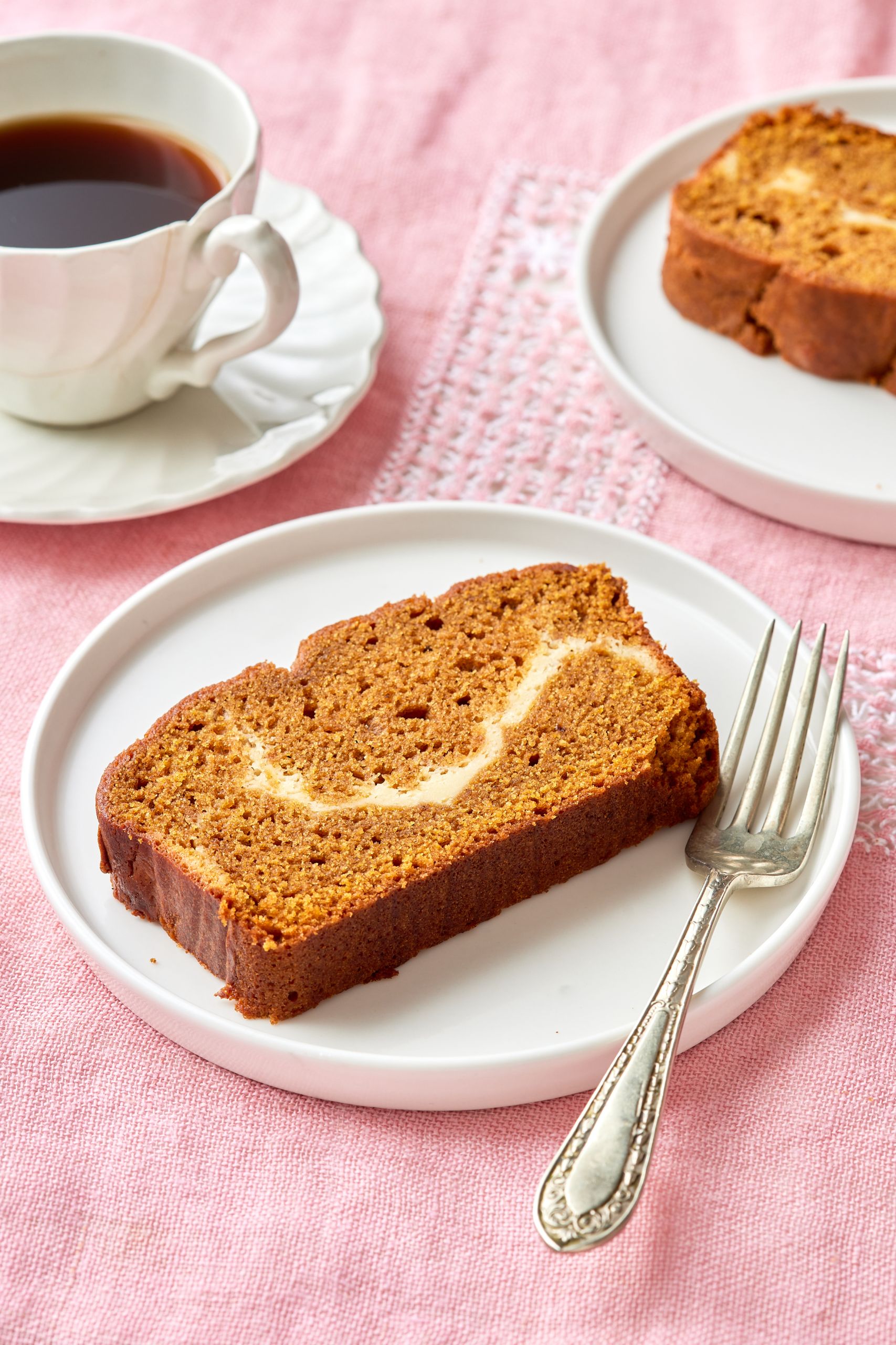 Two slices of Pumpkin Cream Cheese Bread are served with coffee. 