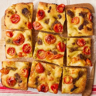 Top down view of golden and bubbly pizza dough focaccia with tomatoes