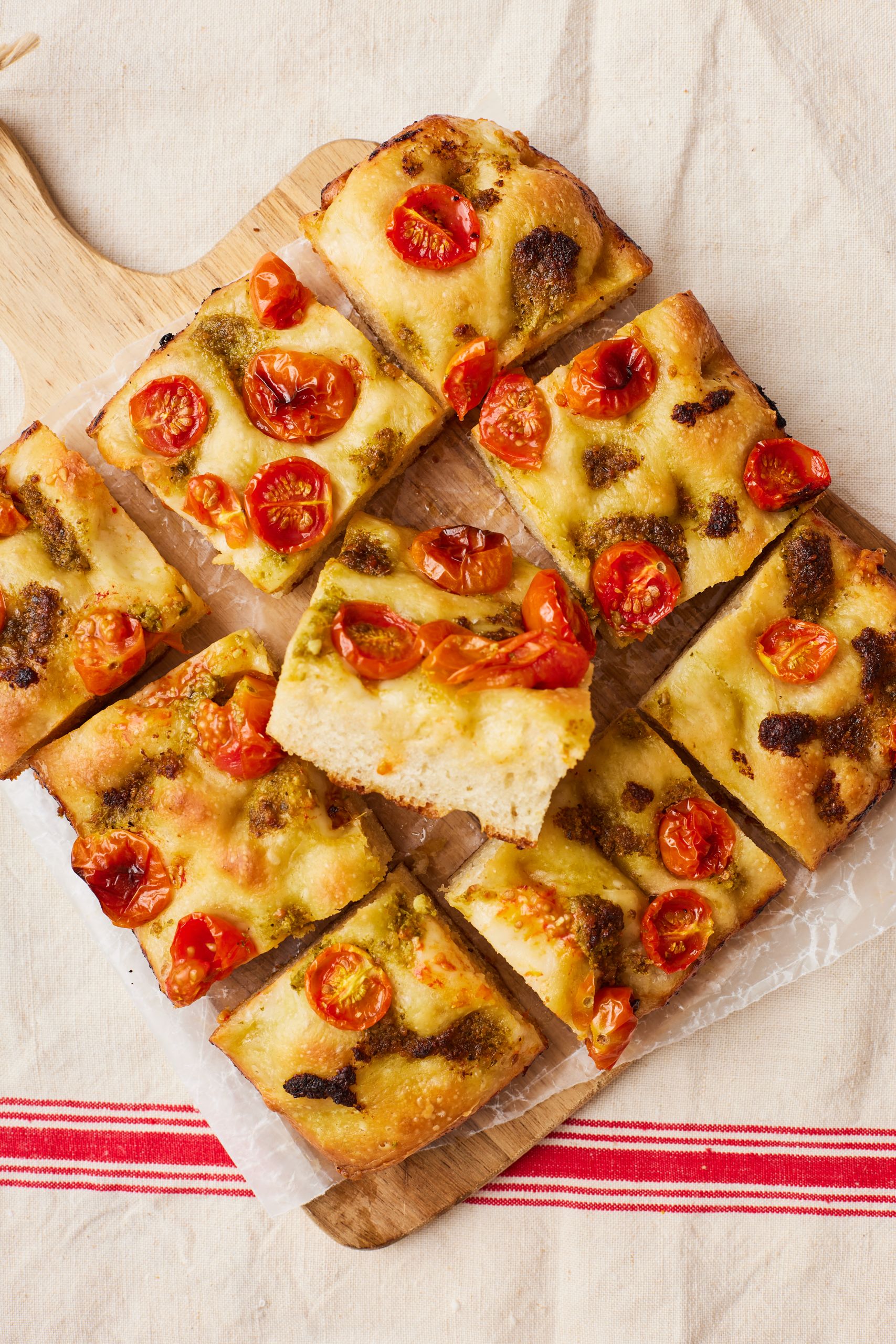 Pizza dough focaccia is cut with one slice showing the bubbly crumb.