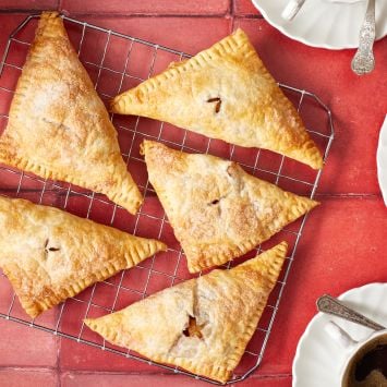 Golden apple turnovers on the cooling rack, served with coffee on the side.